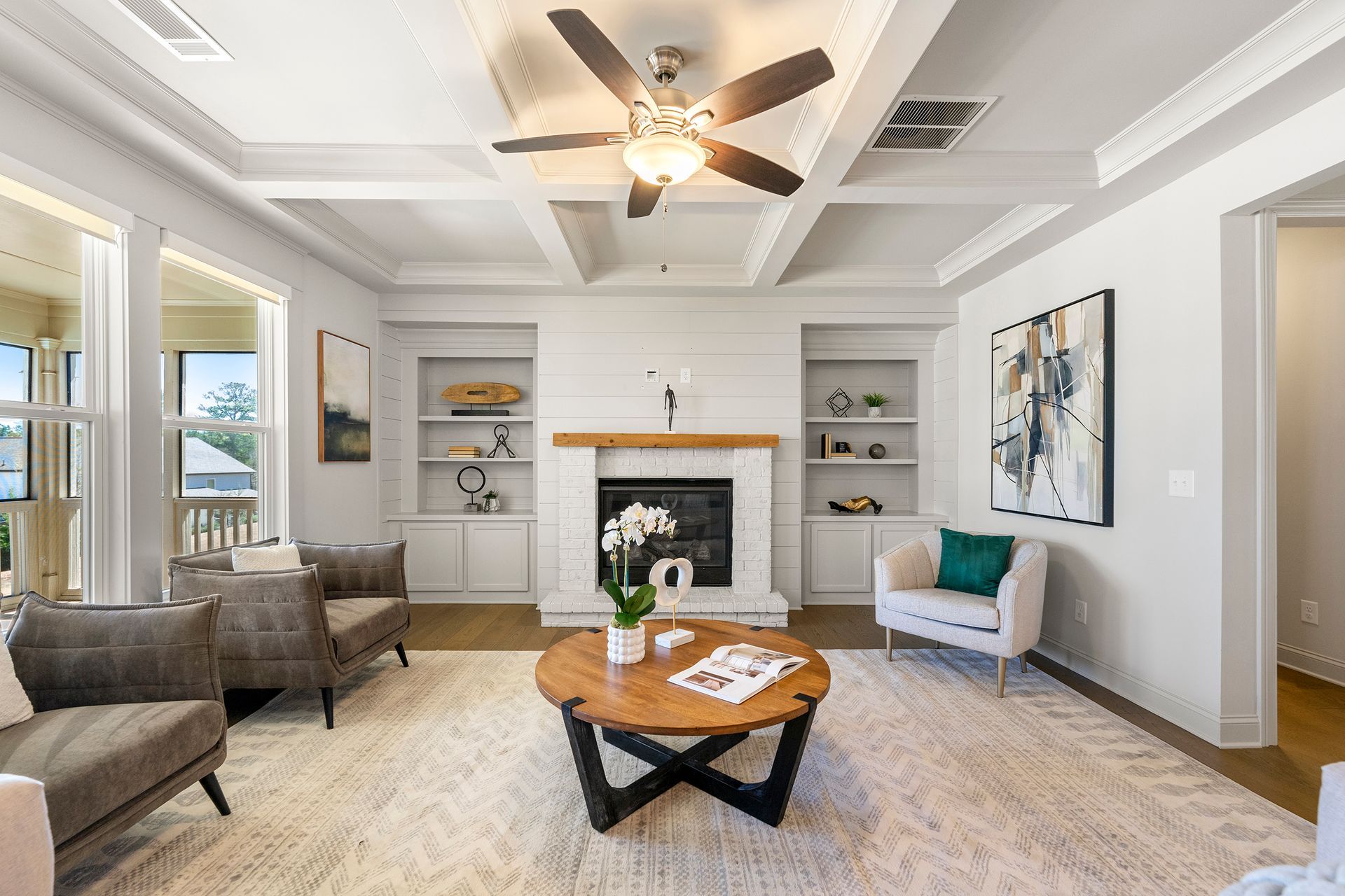 A living room with a fireplace , coffee table , chairs and a ceiling fan.