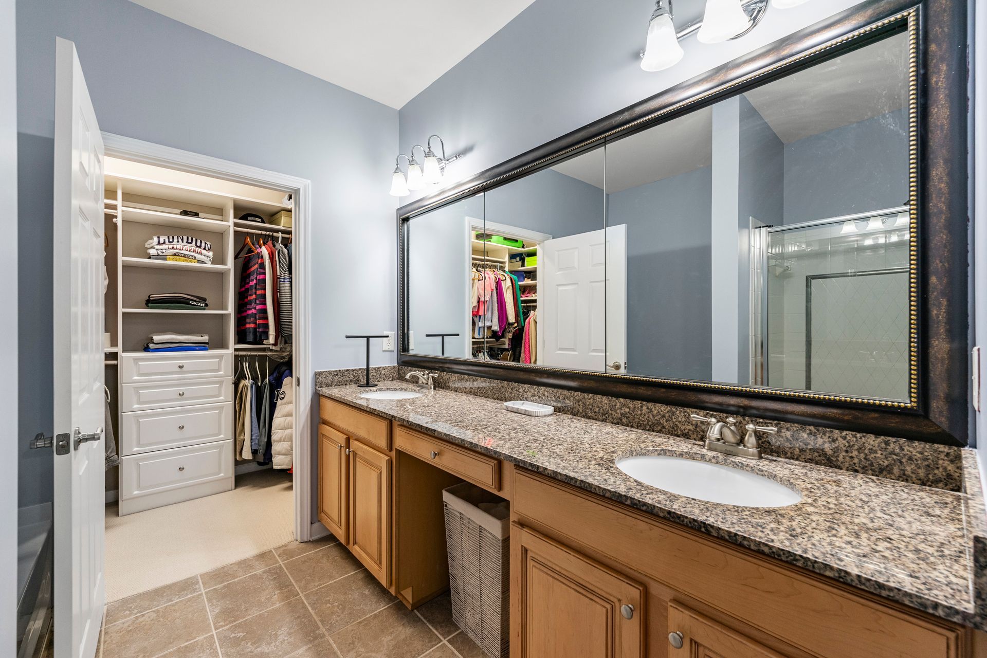A bathroom with two sinks and a walk in closet.