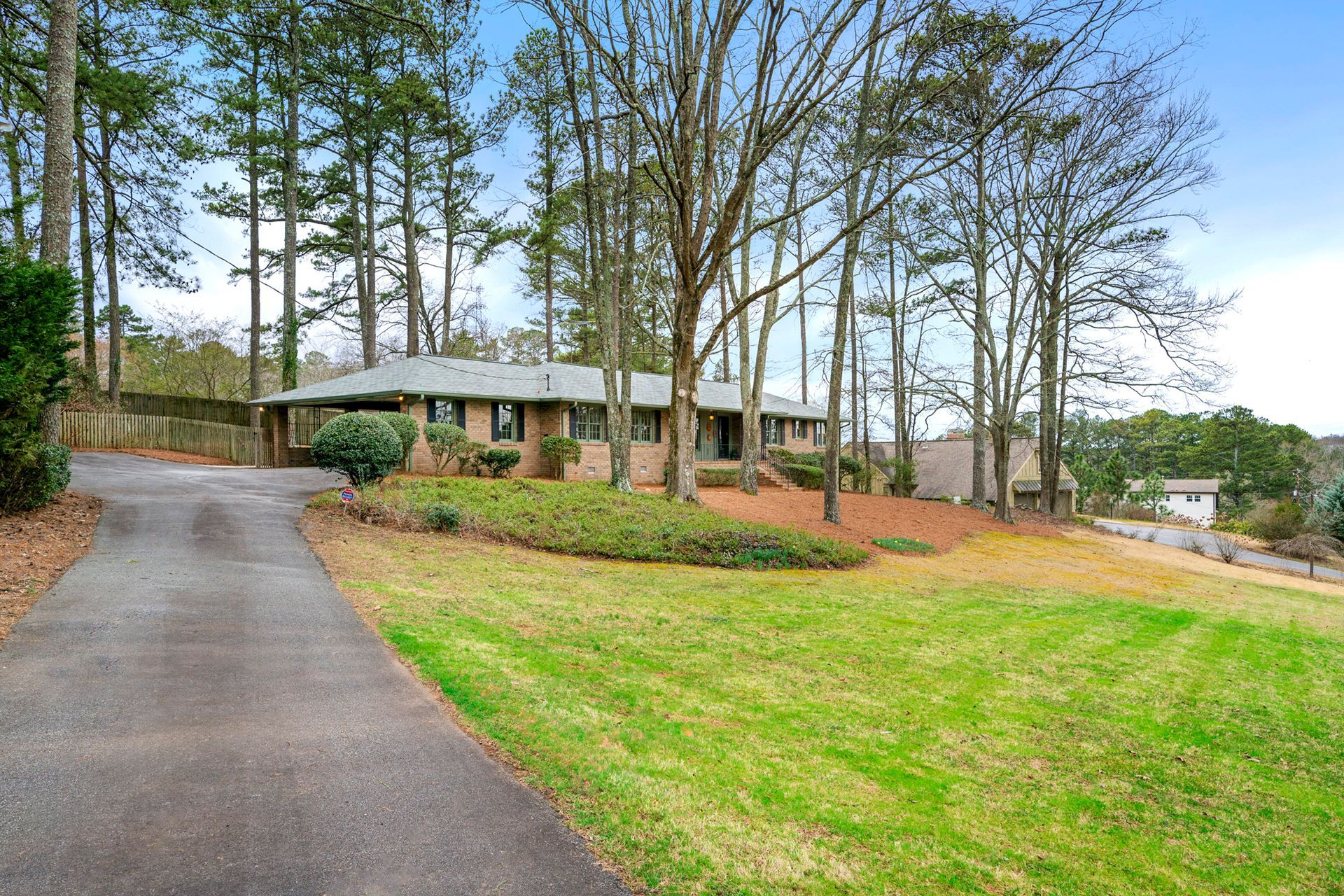 A house with a driveway leading to it is surrounded by trees and grass.
