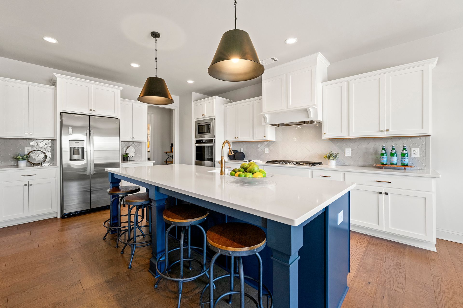 A kitchen with white cabinets and a blue island.