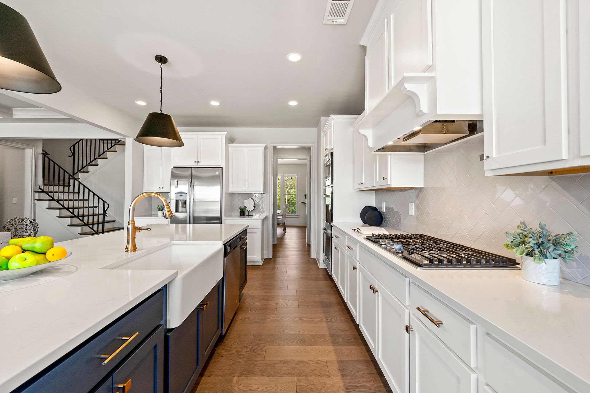 A kitchen with white cabinets , a stove , a sink and a staircase.