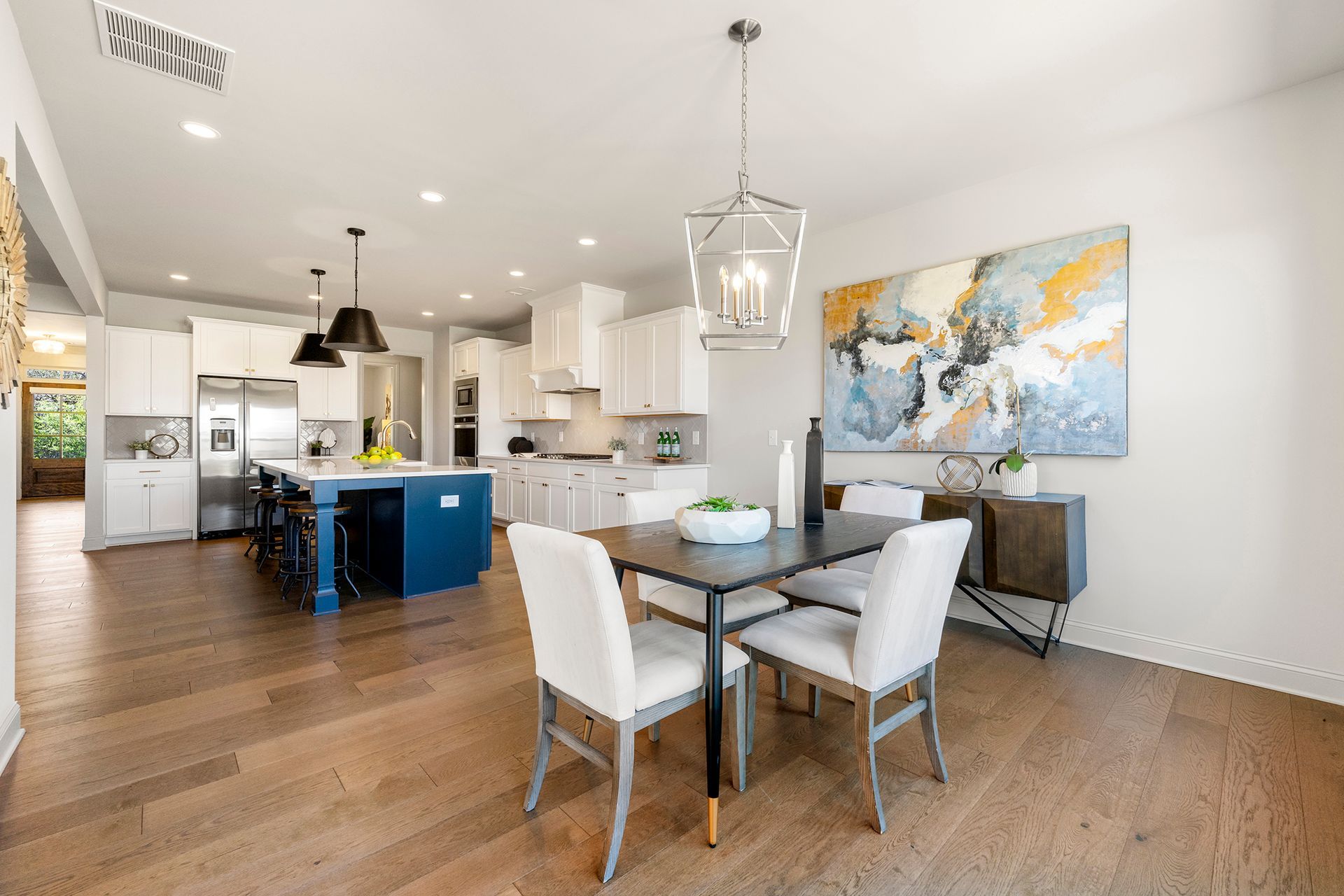 A dining room table and chairs in a kitchen with a painting on the wall.