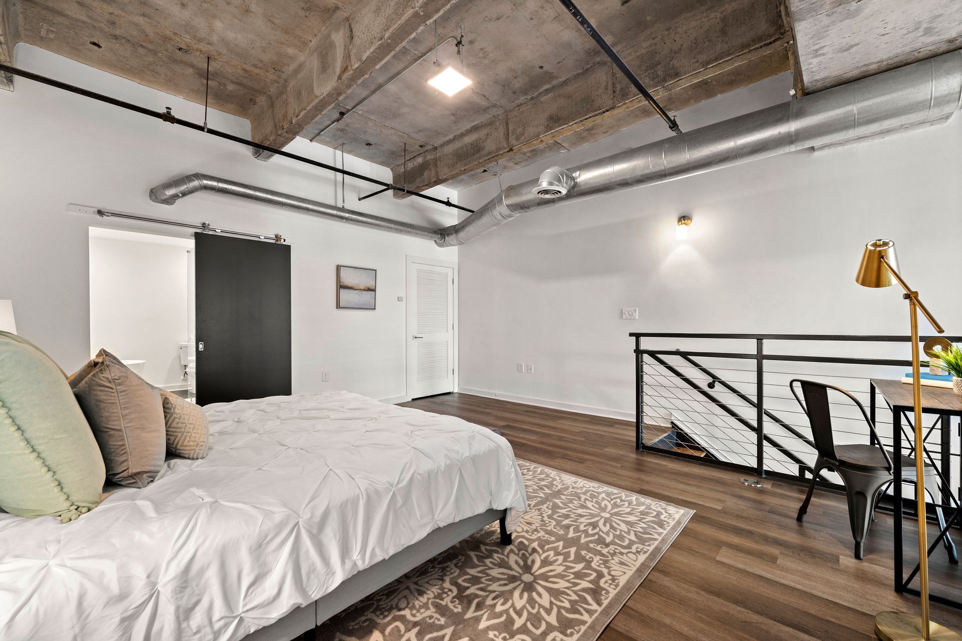 A bedroom with a bed , desk , chair and rug.