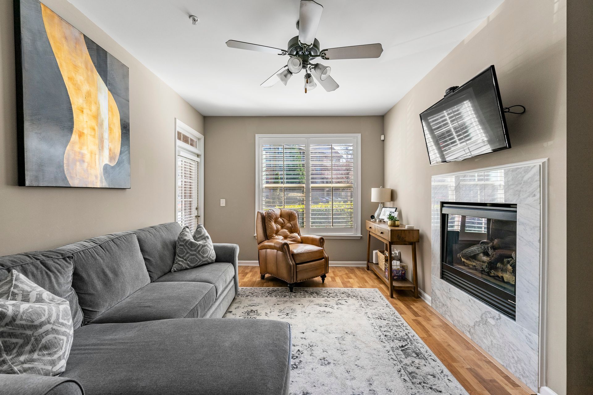 A living room with a couch , chair , fireplace and television.