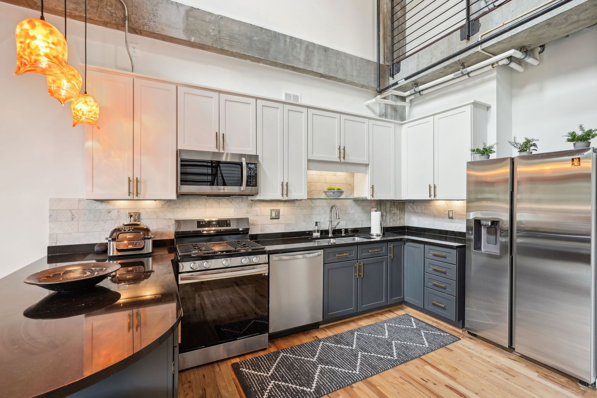Modern kitchen with white and dark gray cabinets, stainless steel appliances, and a black countertop.
