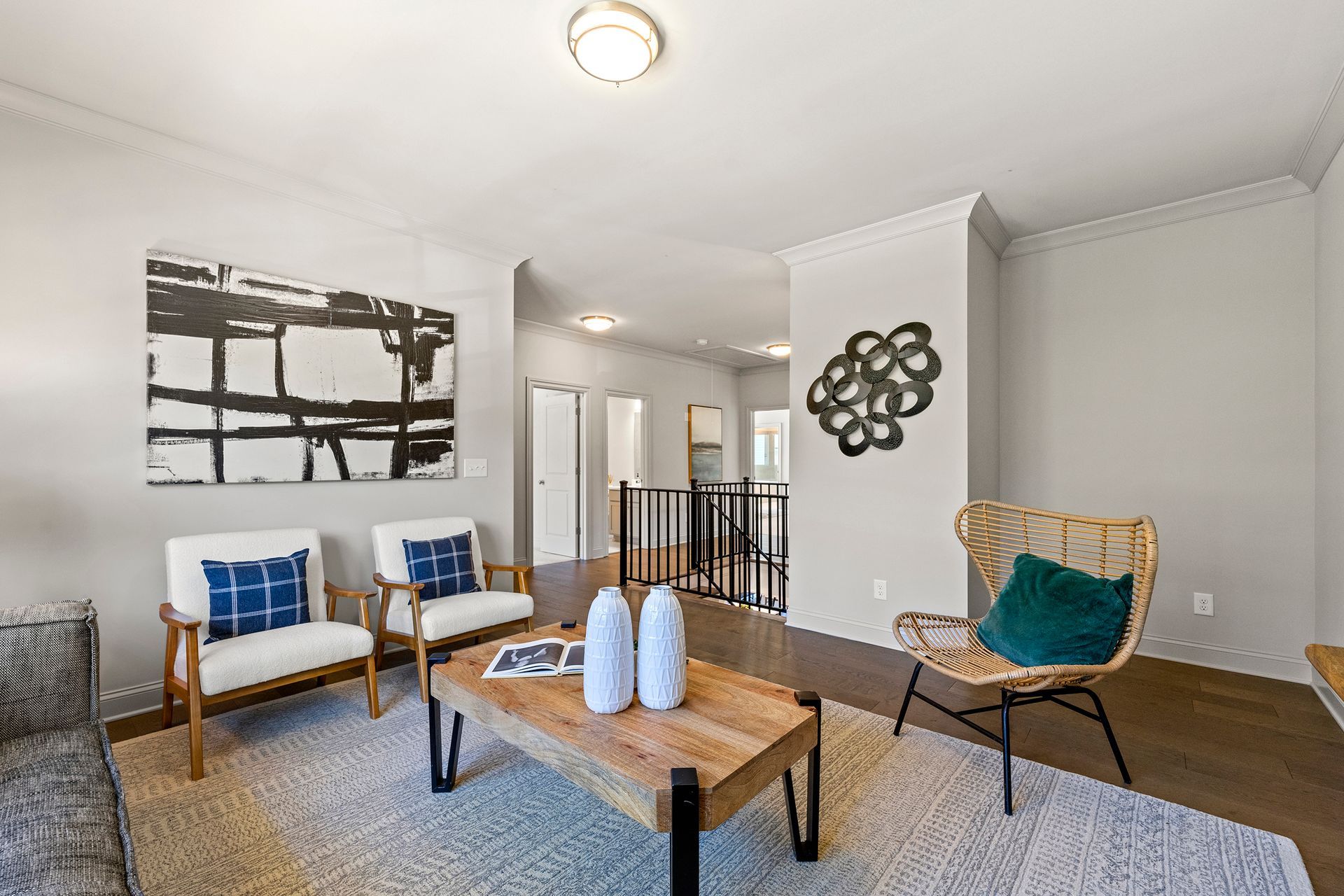 A living room with a coffee table , chairs , and a painting on the wall.
