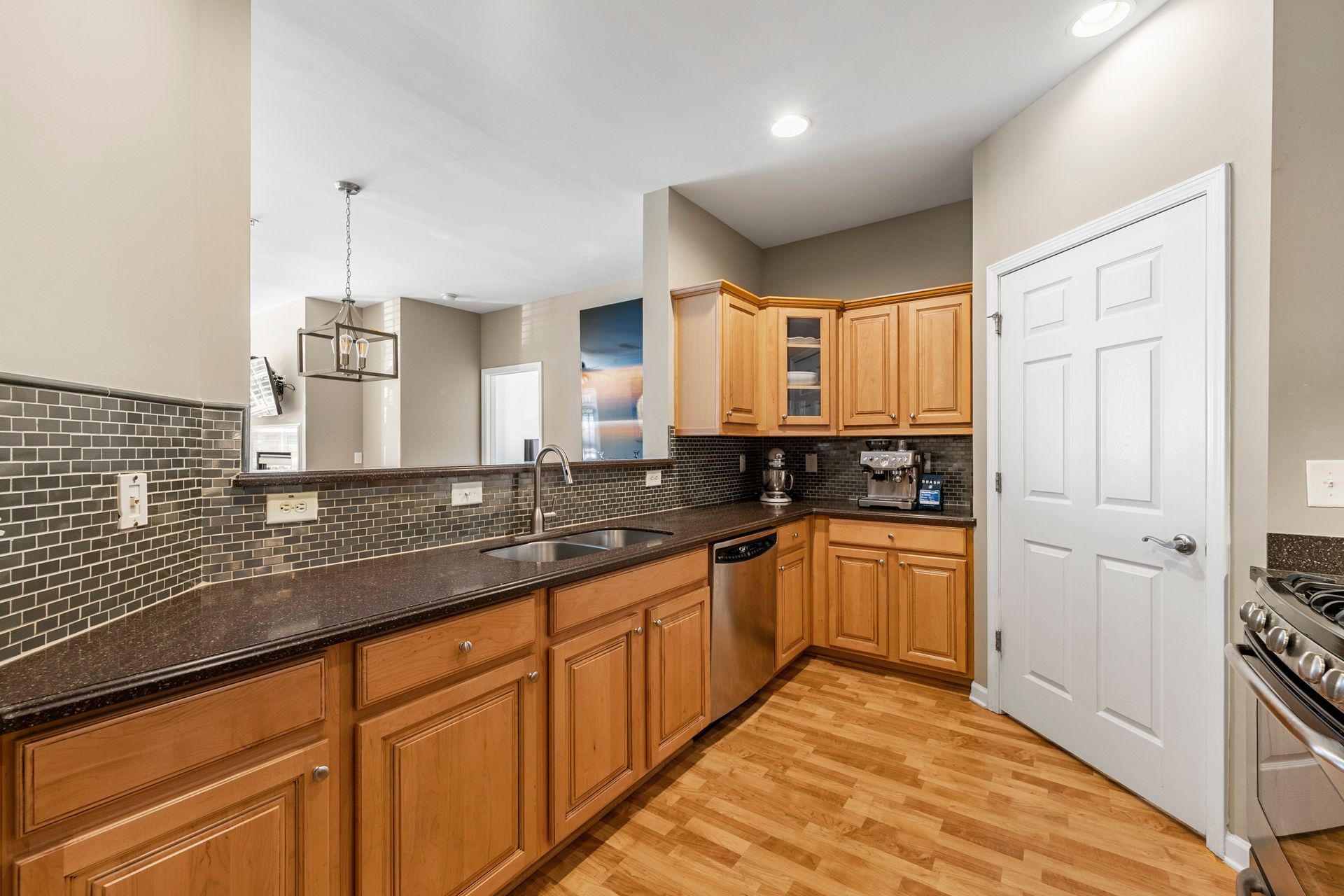 A kitchen with wooden cabinets , granite counter tops , and stainless steel appliances.