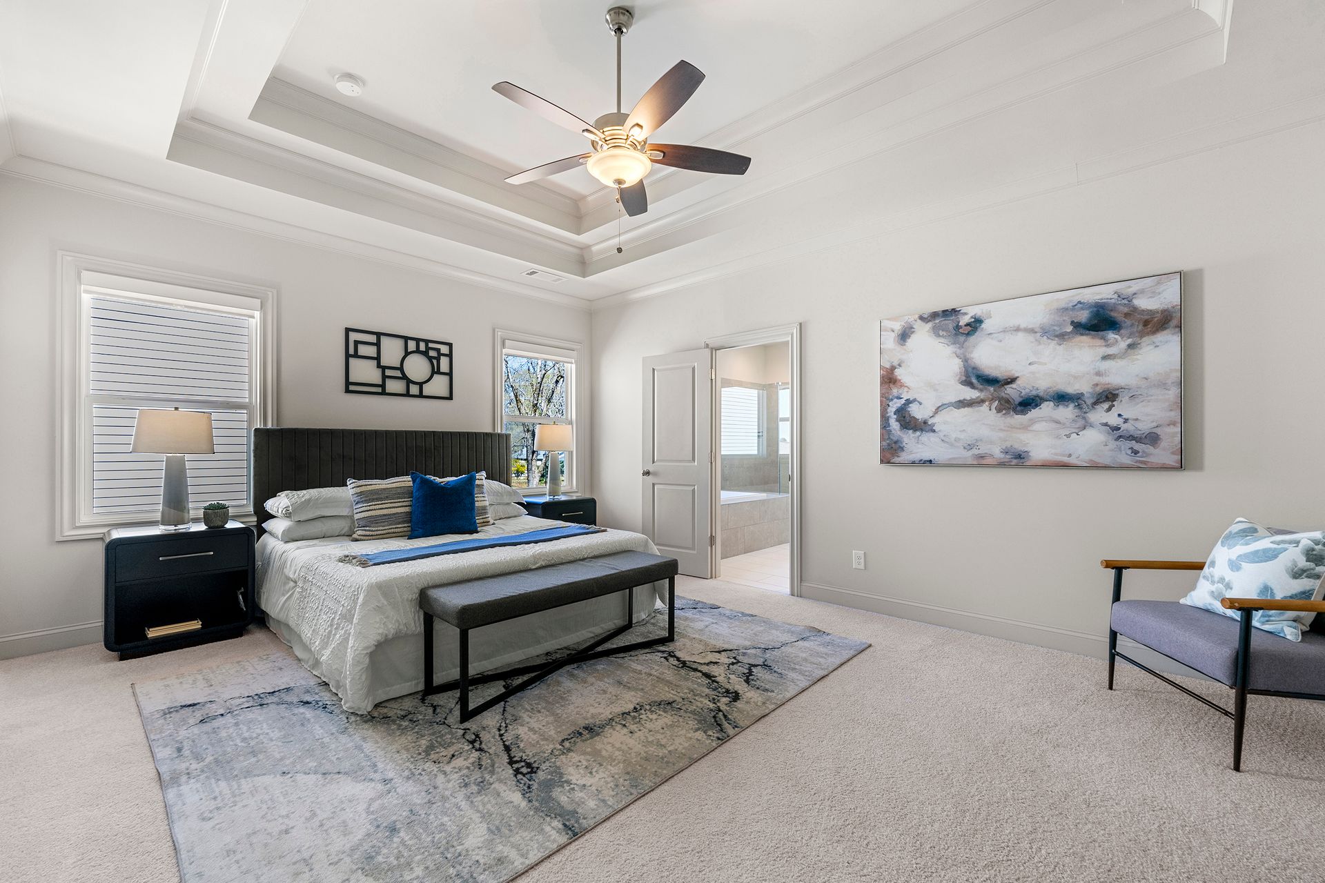 A bedroom with a bed , chair and ceiling fan.