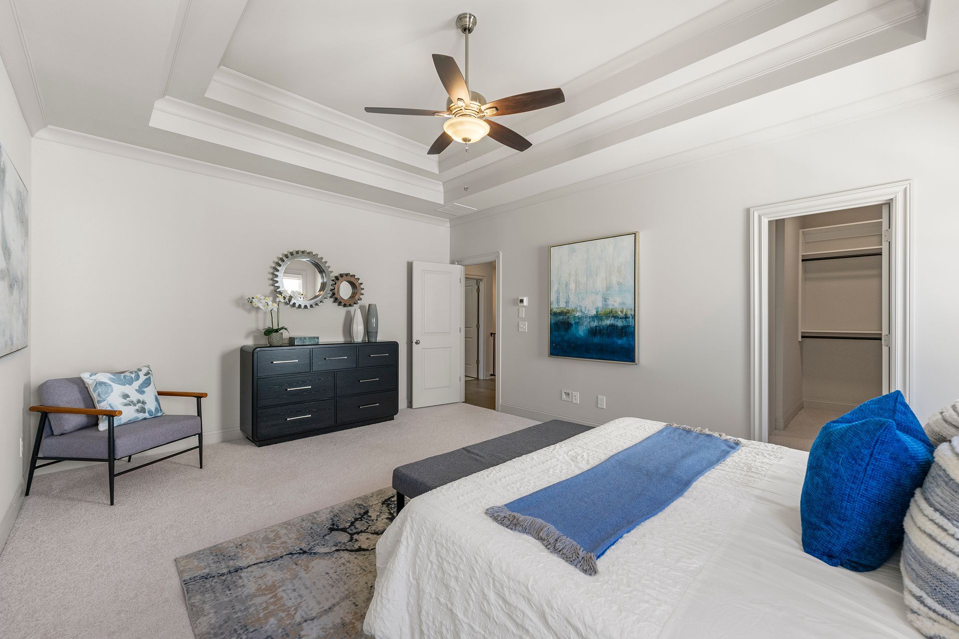 A bedroom with a bed , dresser , chair and ceiling fan.