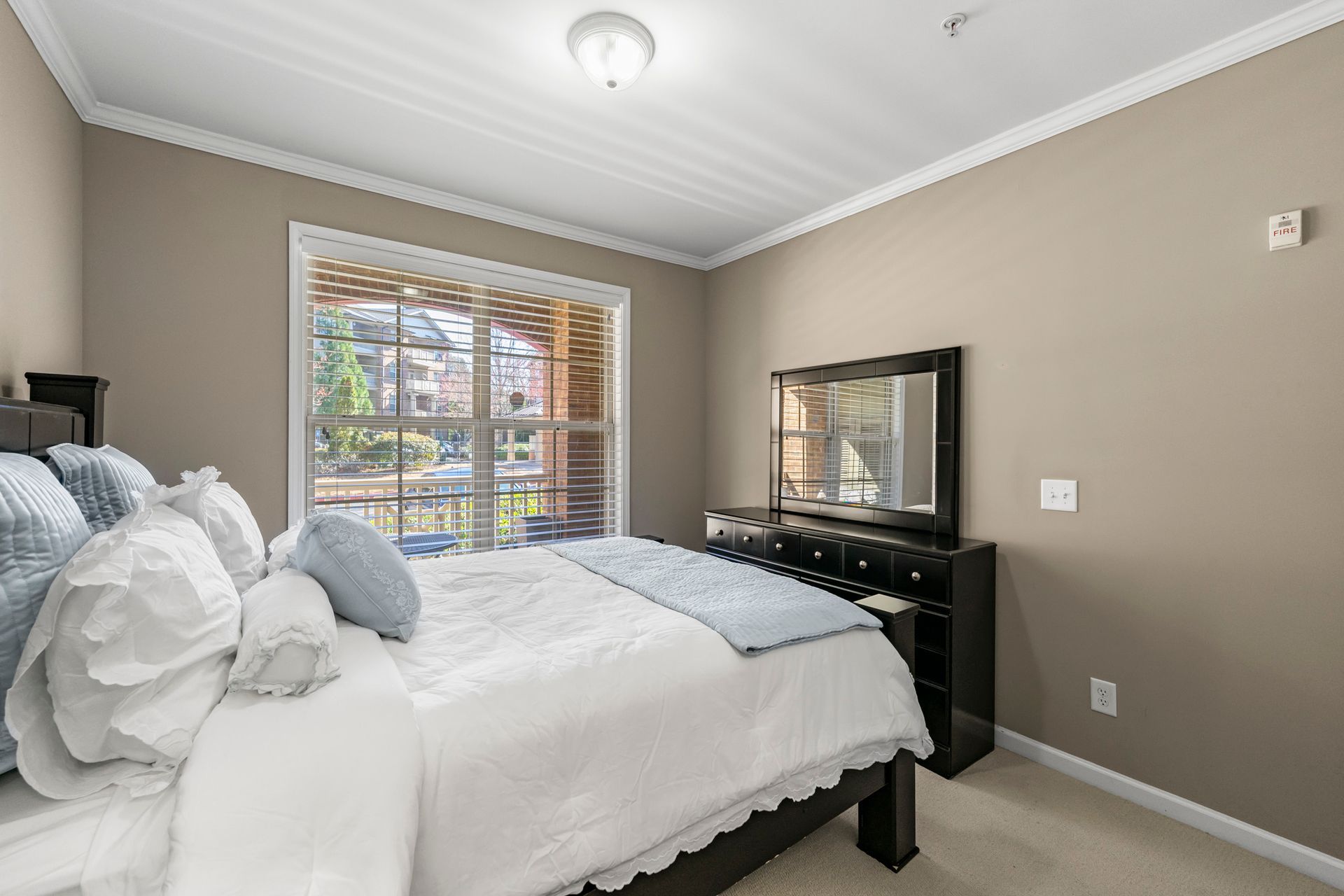 A bedroom with a king size bed , dresser , mirror and television.