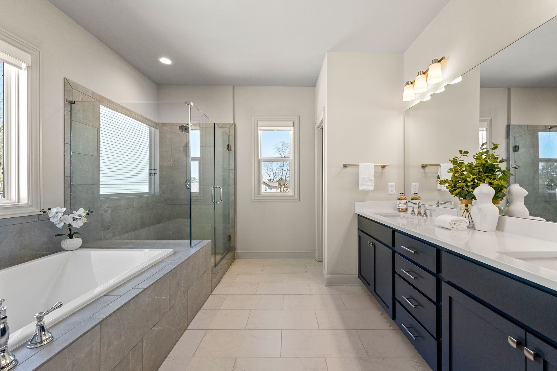 A bathroom with a tub , sink , mirror and shower.