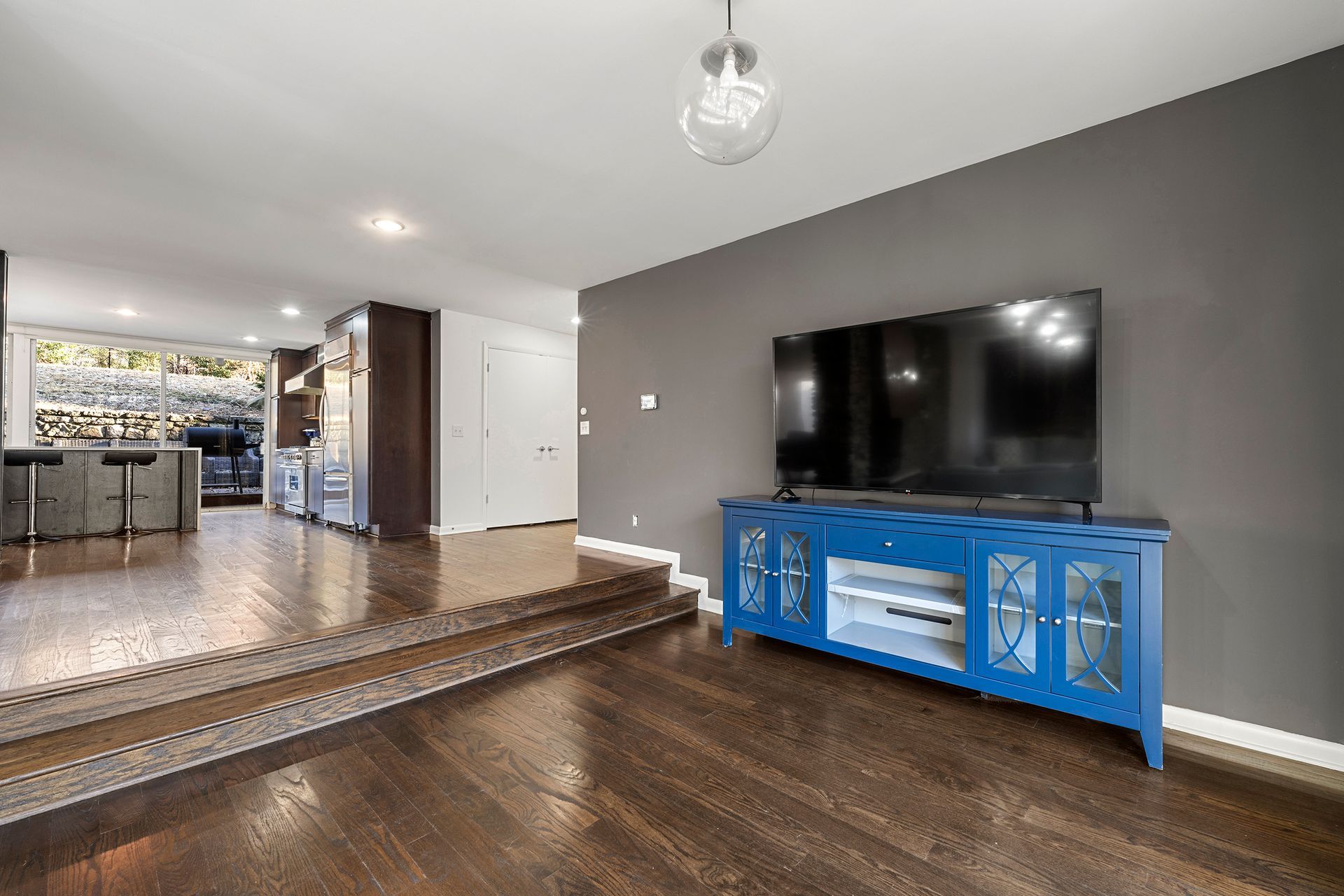 A living room with hardwood floors , a blue entertainment center and a flat screen tv.