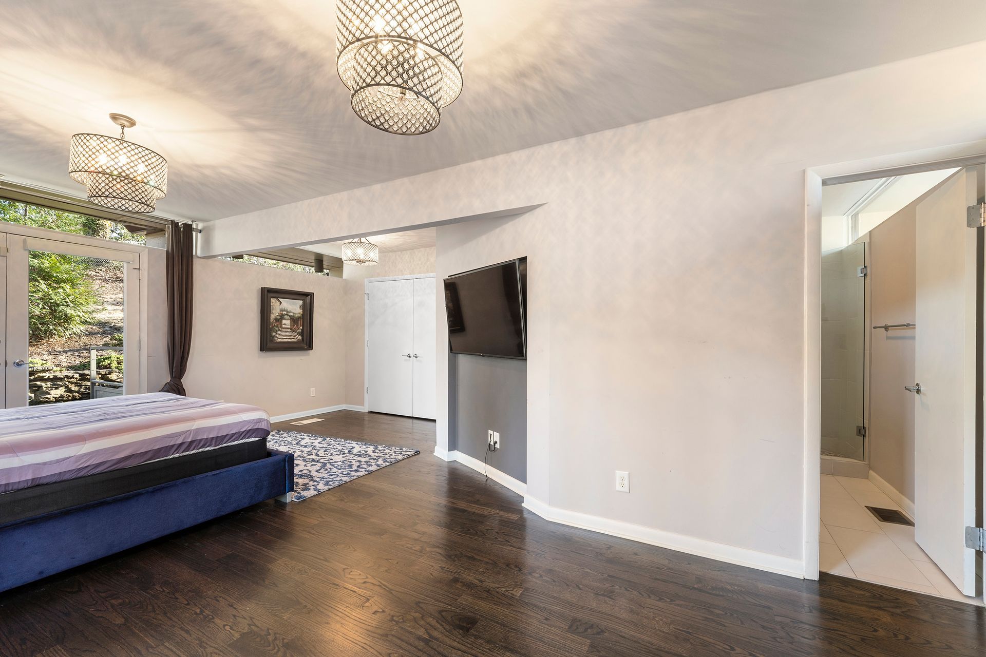 A bedroom with a large bed and a television on the wall.
