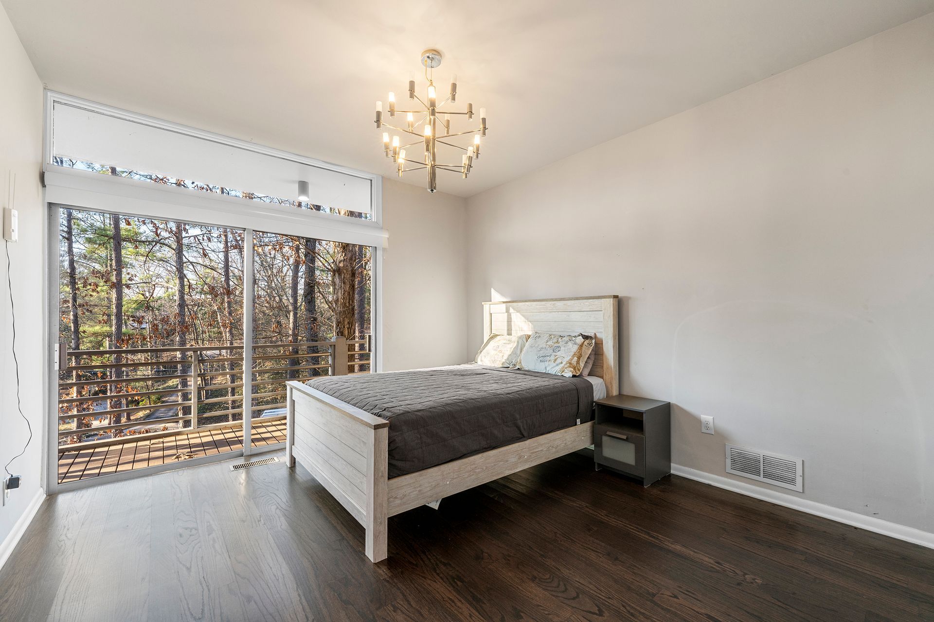 A bedroom with a bed , nightstand , and sliding glass doors.