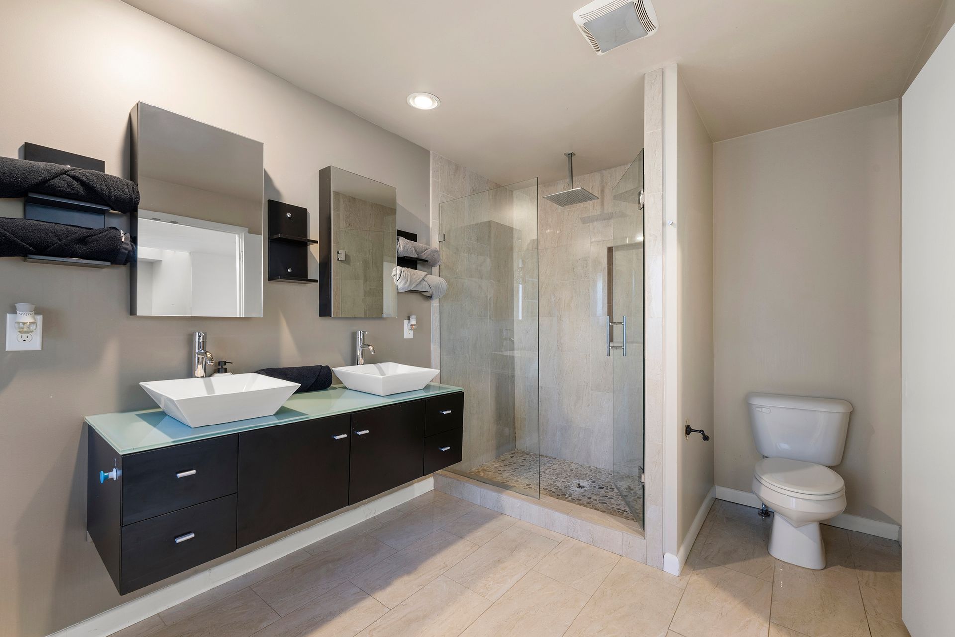 A bathroom with two sinks , a toilet and a walk in shower.