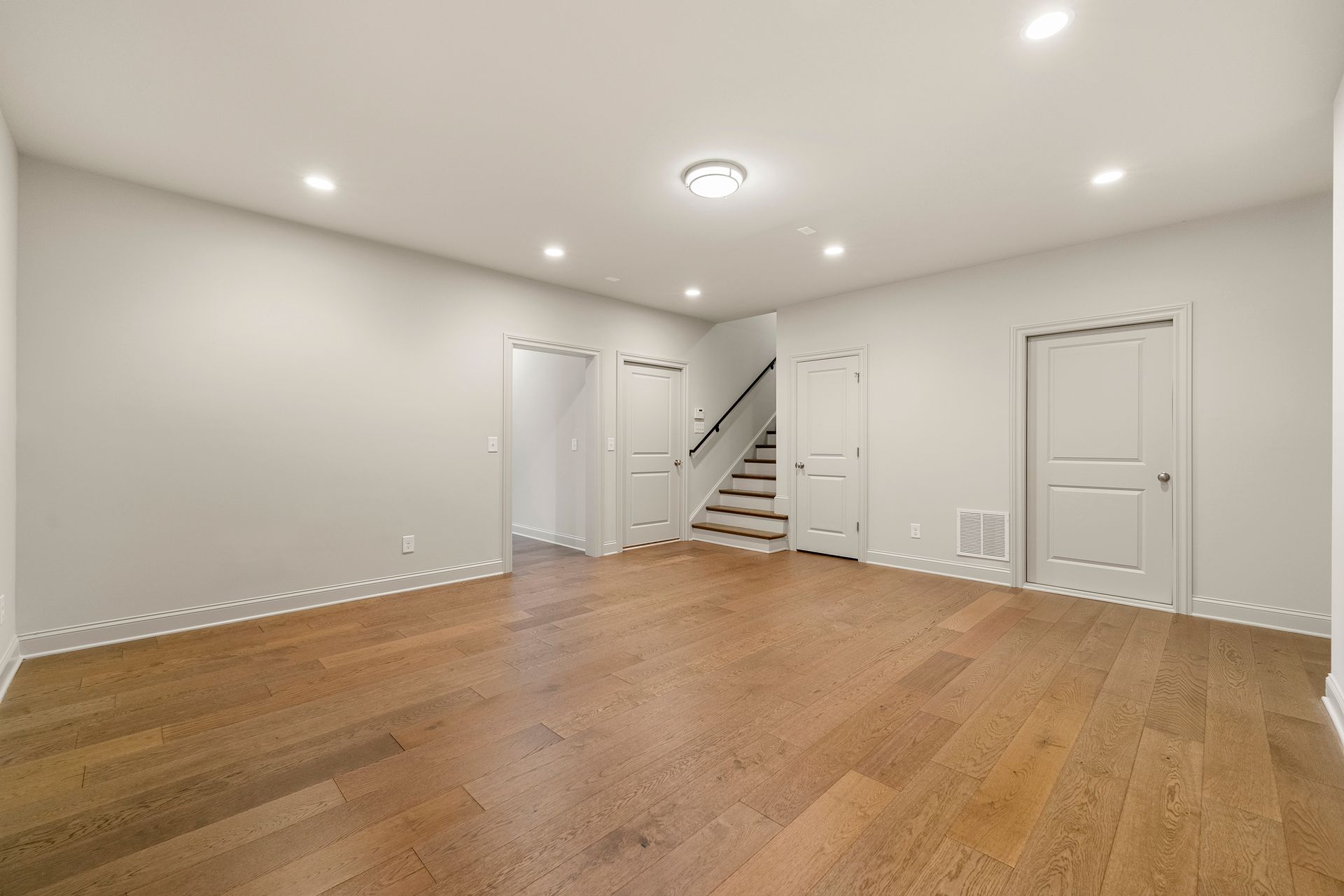 A large empty room with hardwood floors and white walls.