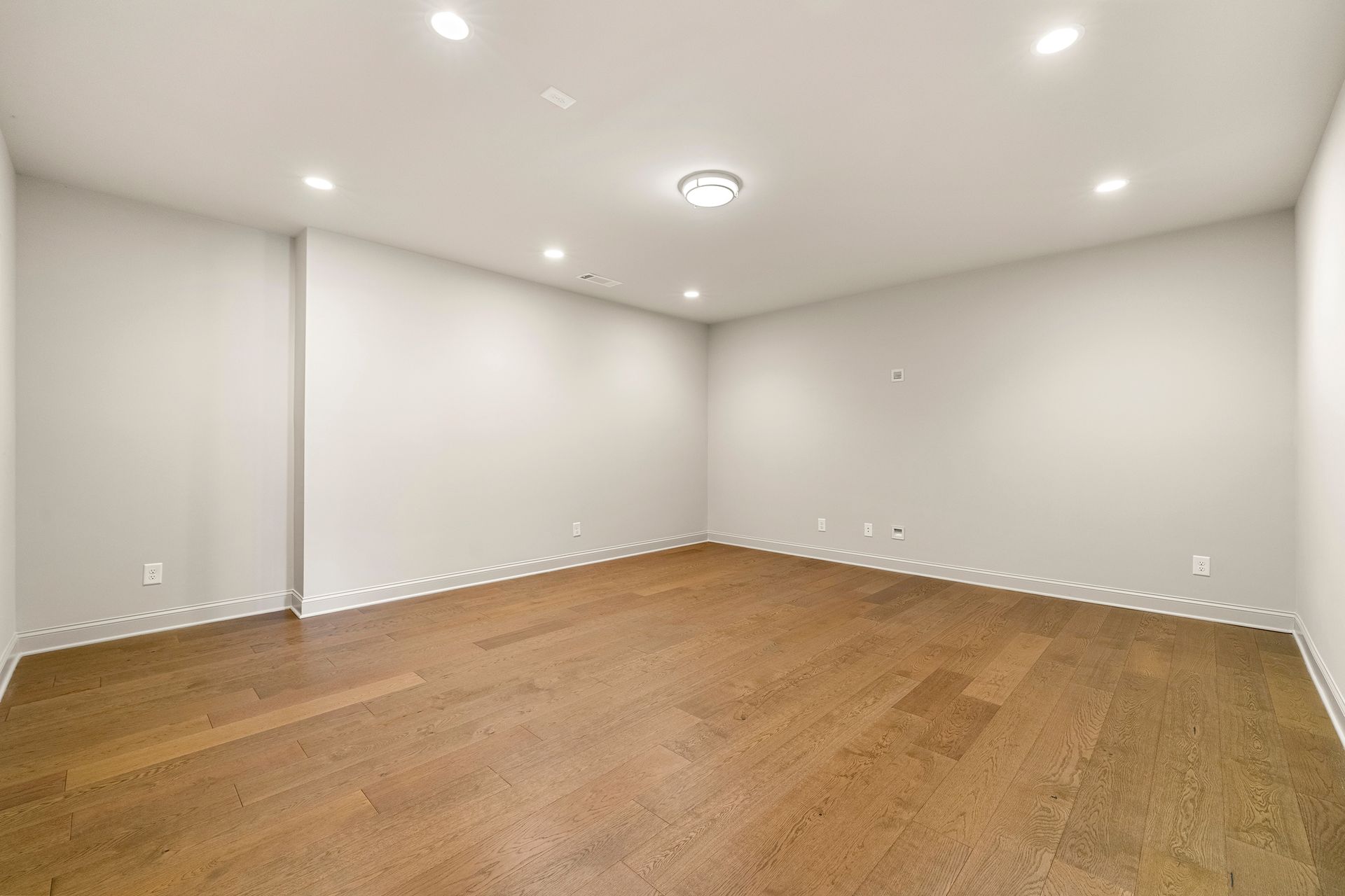 An empty room with hardwood floors and white walls.