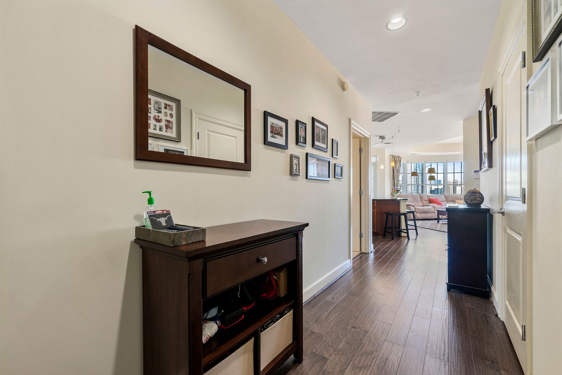 A hallway with hardwood floors and a mirror on the wall.