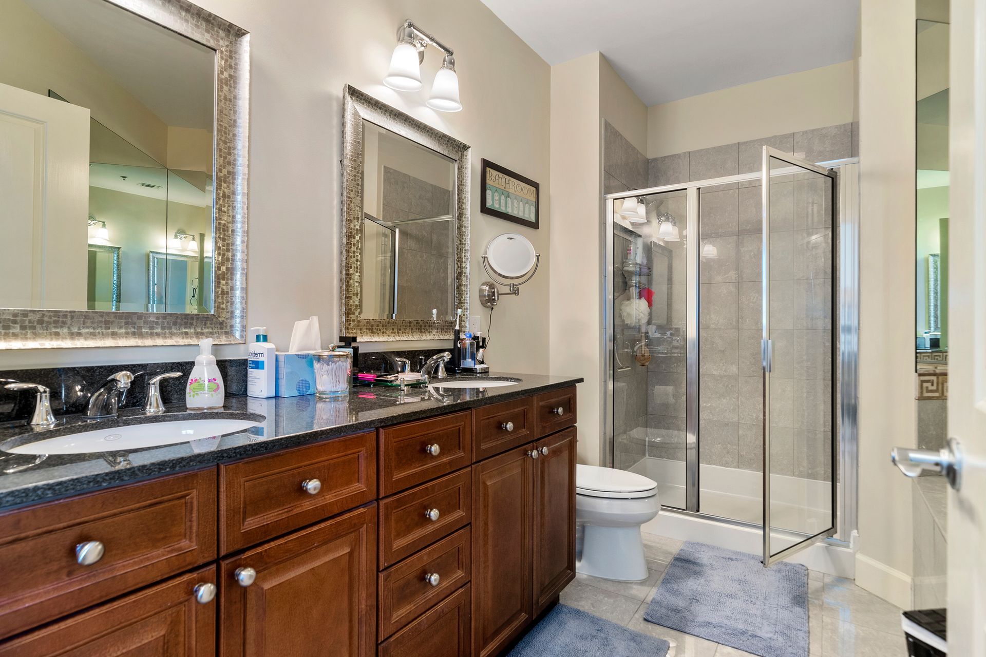 A bathroom with two sinks , a toilet , and a walk in shower.