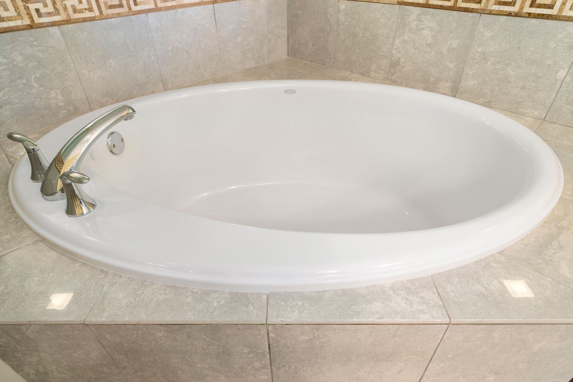 A white bathtub is sitting on a tiled floor in a bathroom.