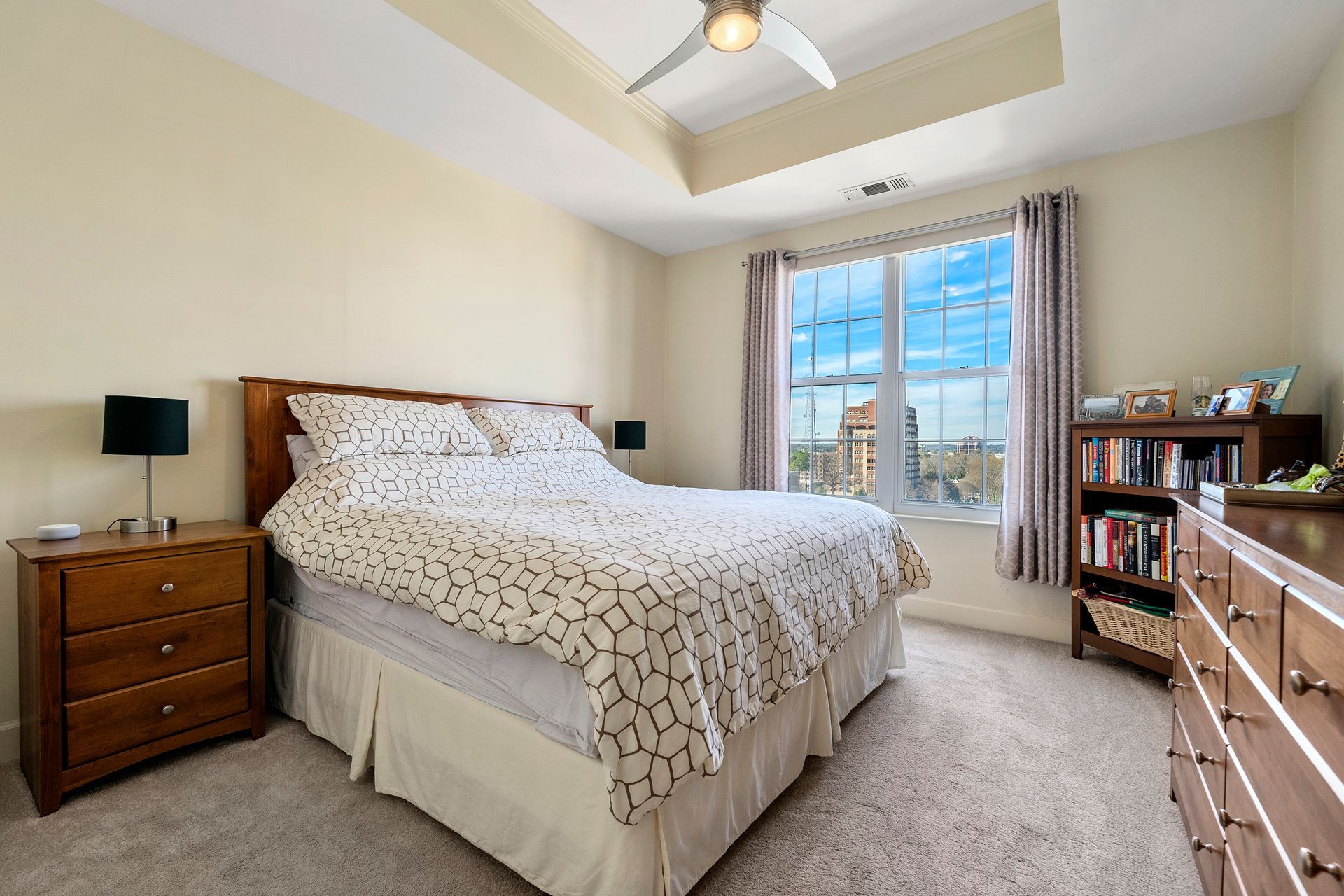 A bedroom with a king size bed , nightstand , dresser and window.