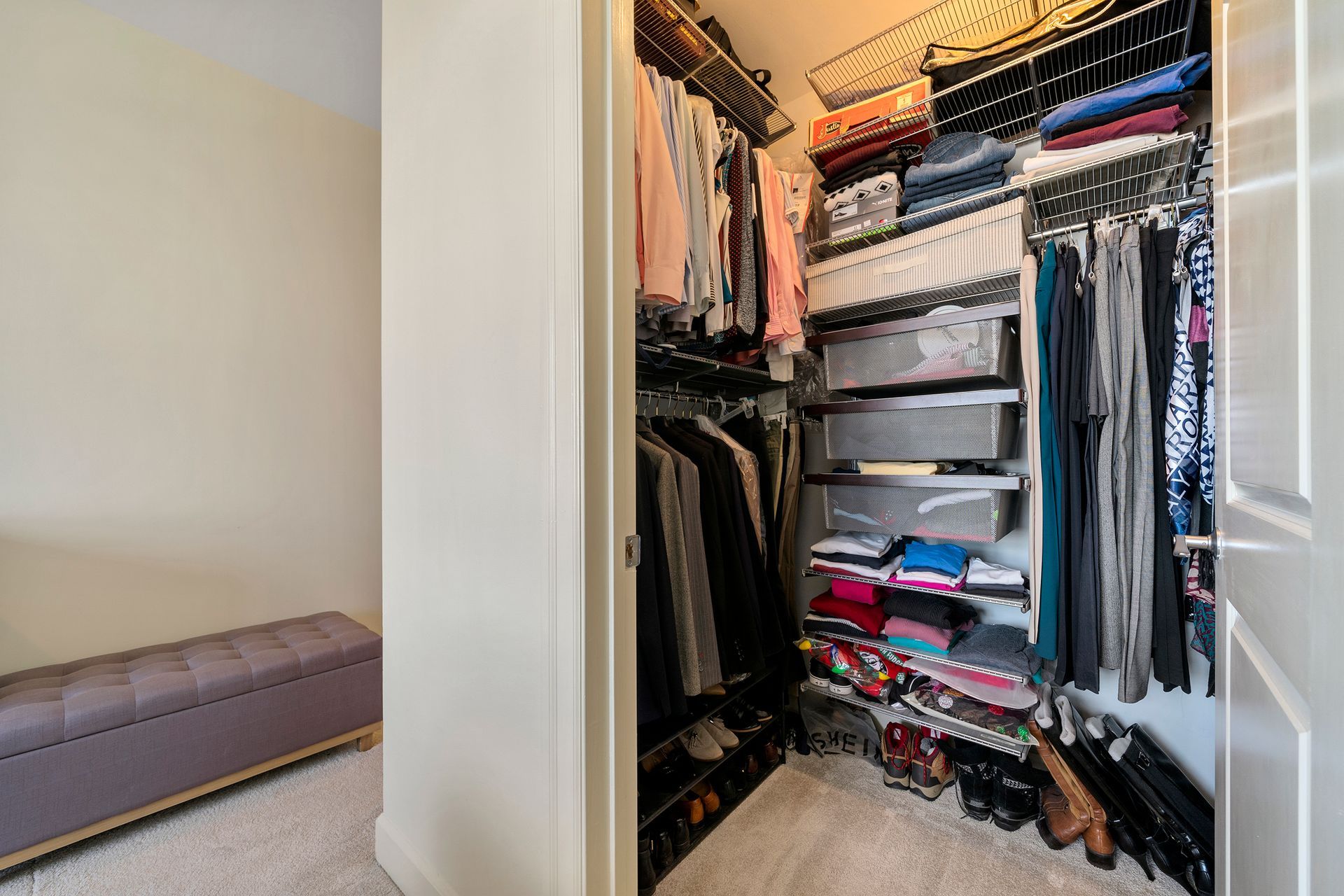 A walk in closet filled with lots of clothes and shoes.