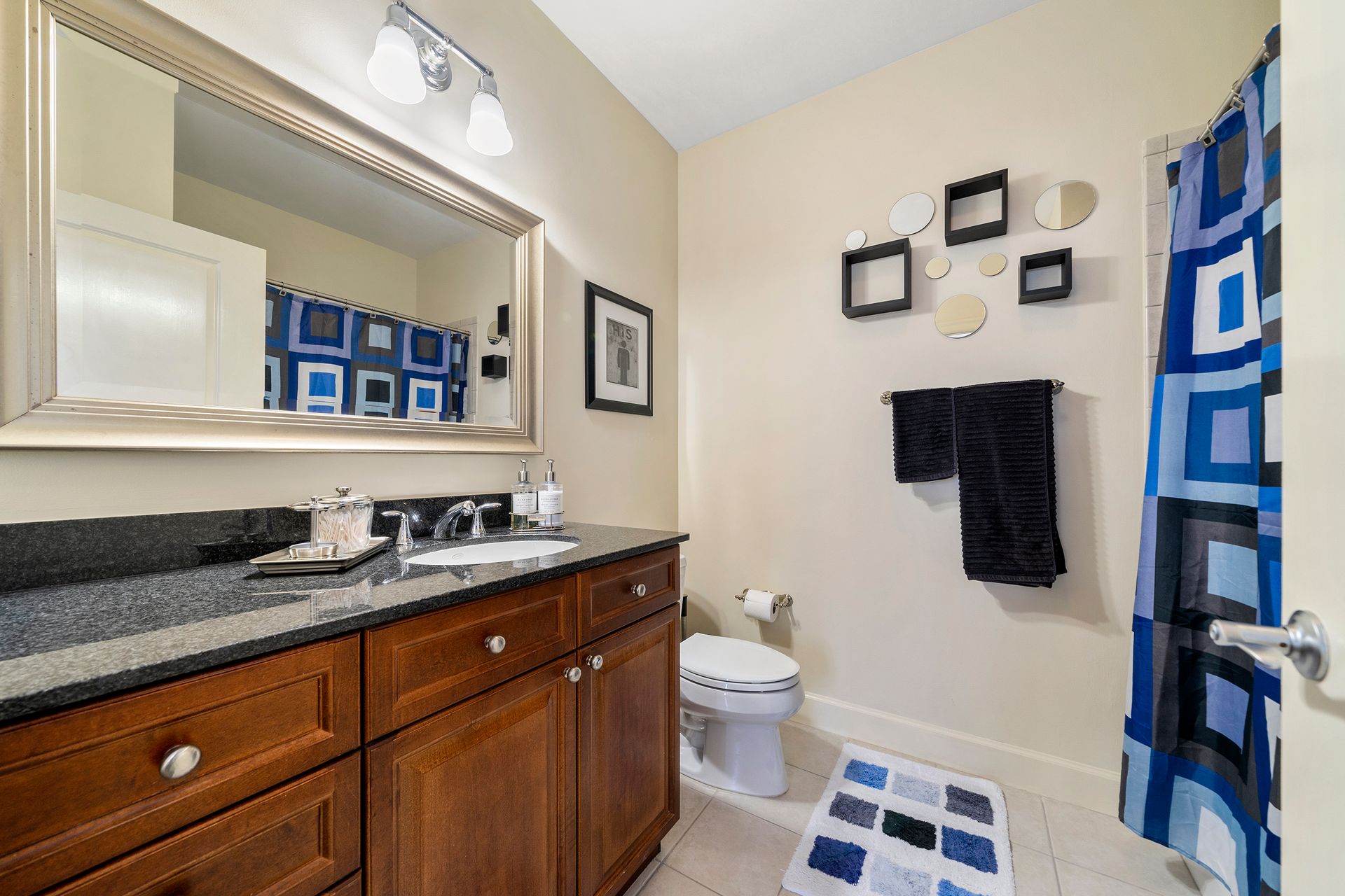 A bathroom with a sink , toilet , shower curtain and mirror.