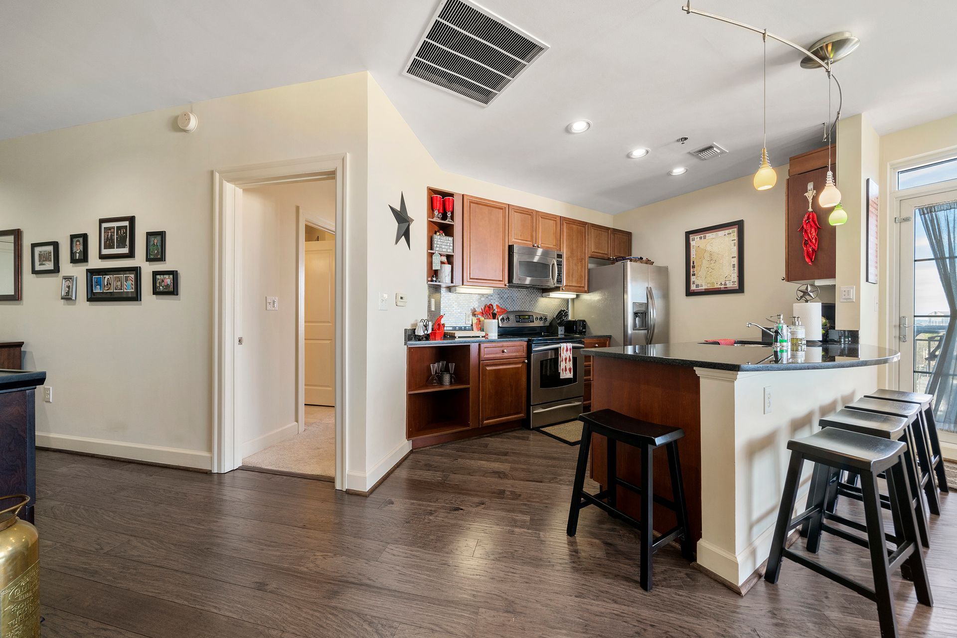 A kitchen with wooden cabinets , stainless steel appliances , a refrigerator and a bar.