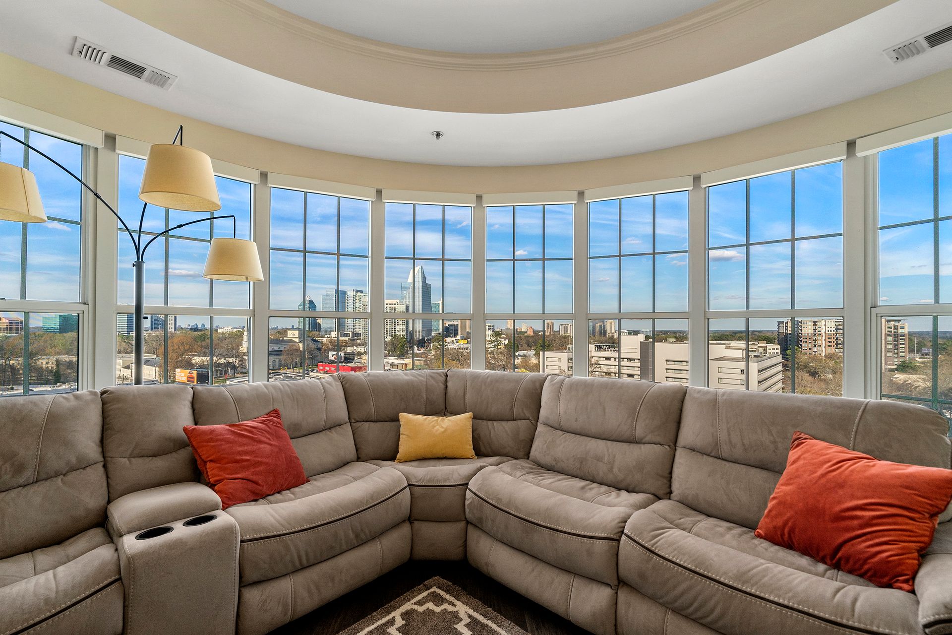 A living room with a large sectional couch and lots of windows.