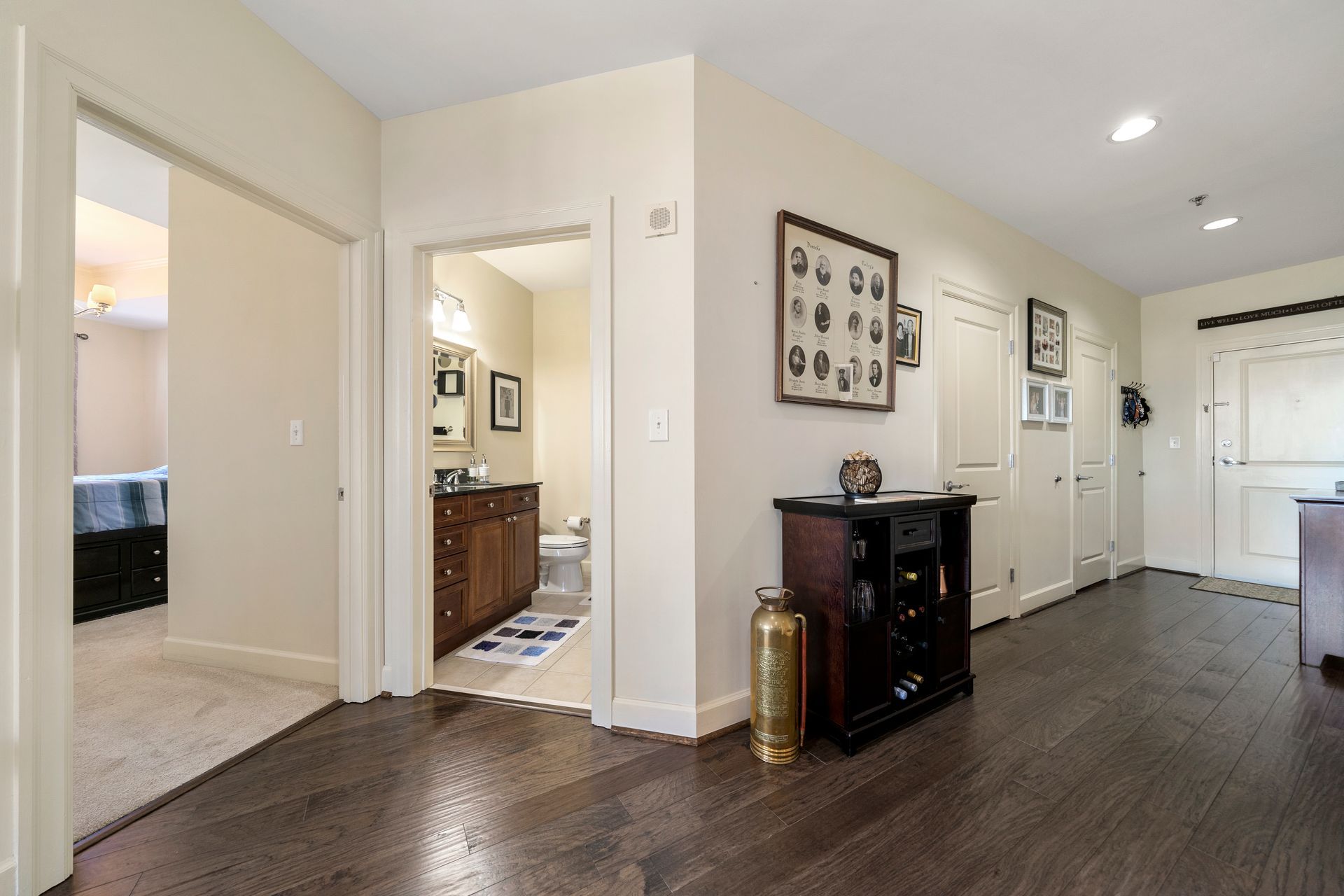 A hallway in a house with hardwood floors leading to a bathroom.