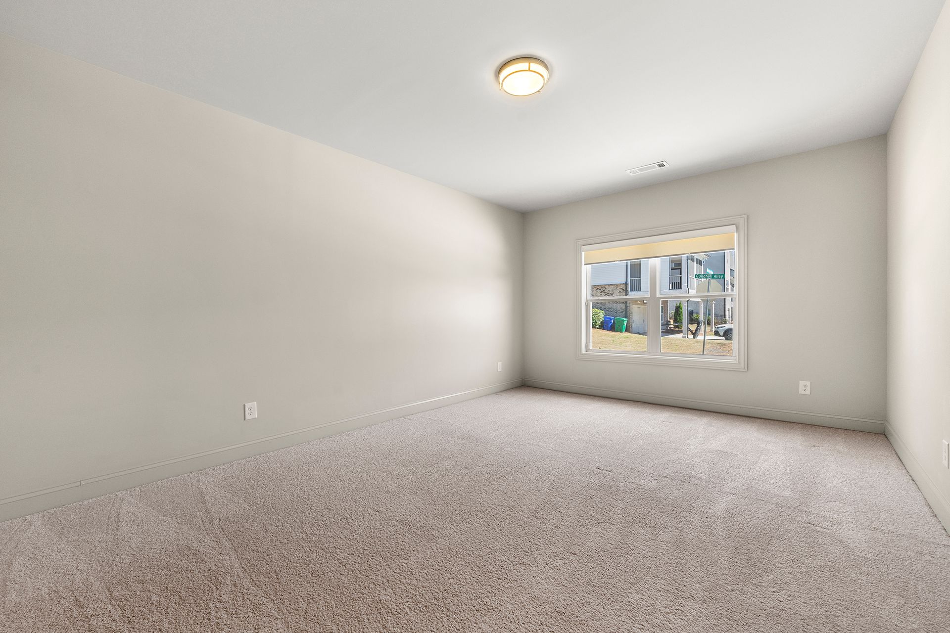 An empty bedroom with a window and carpet.