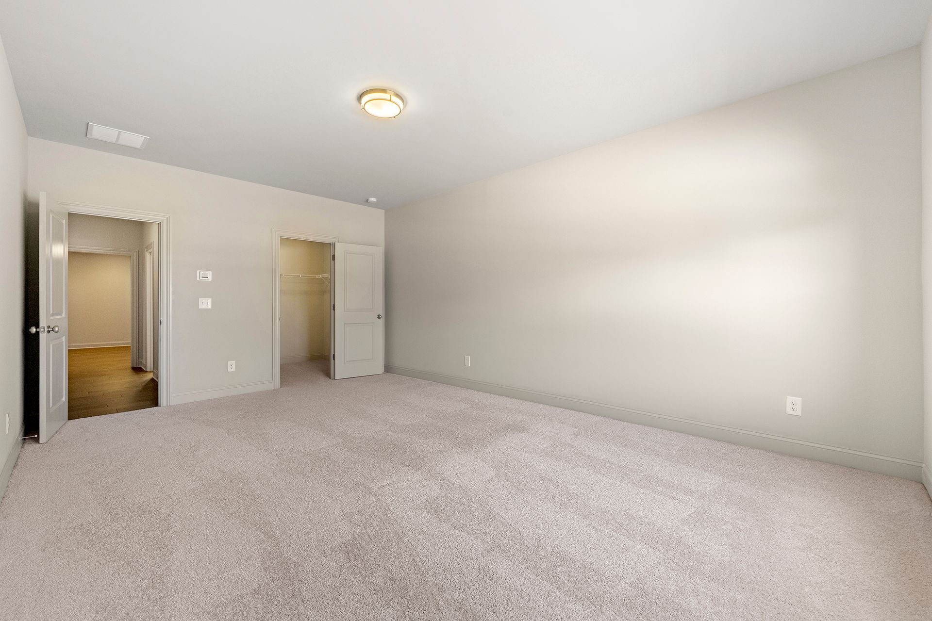 An empty bedroom with a carpeted floor and white walls.