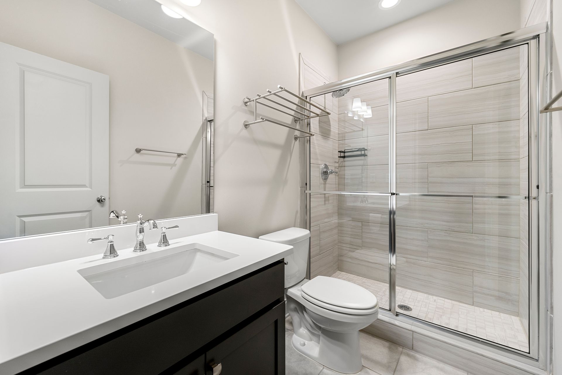 A bathroom with a toilet , sink , mirror and walk in shower.