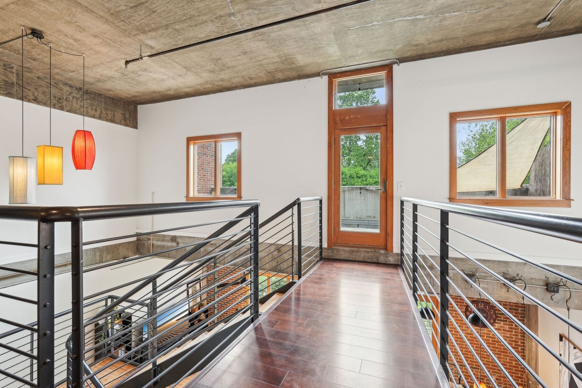 Interior loft space with railings, windows, and hanging pendant lights.