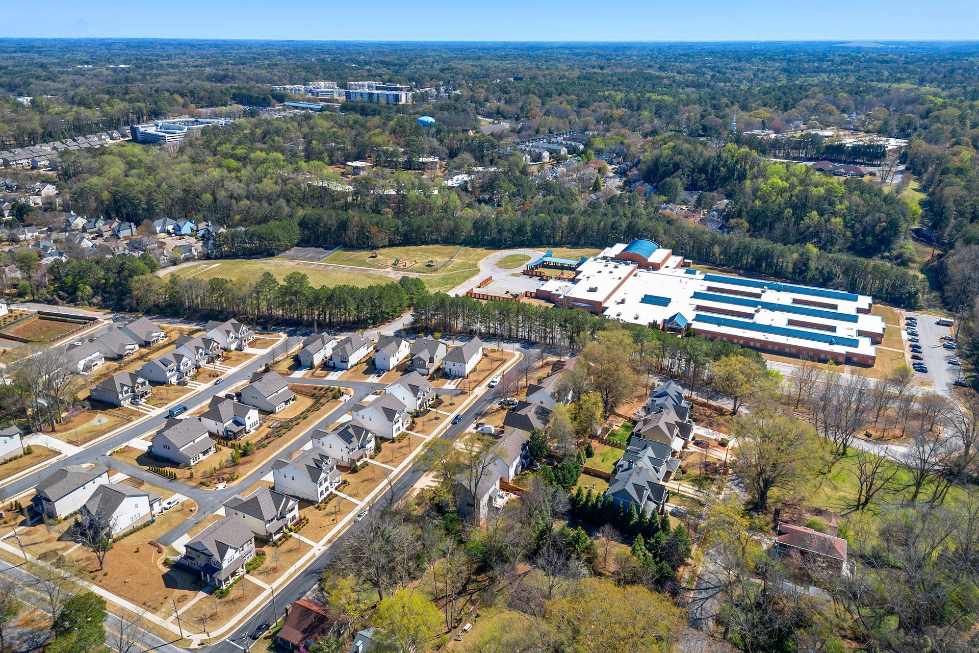 An aerial view of a residential area with a school in the background.