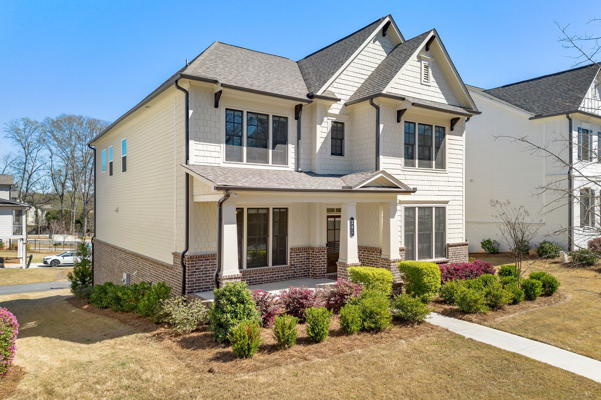 A white house with a gray roof is sitting on top of a lush green field.