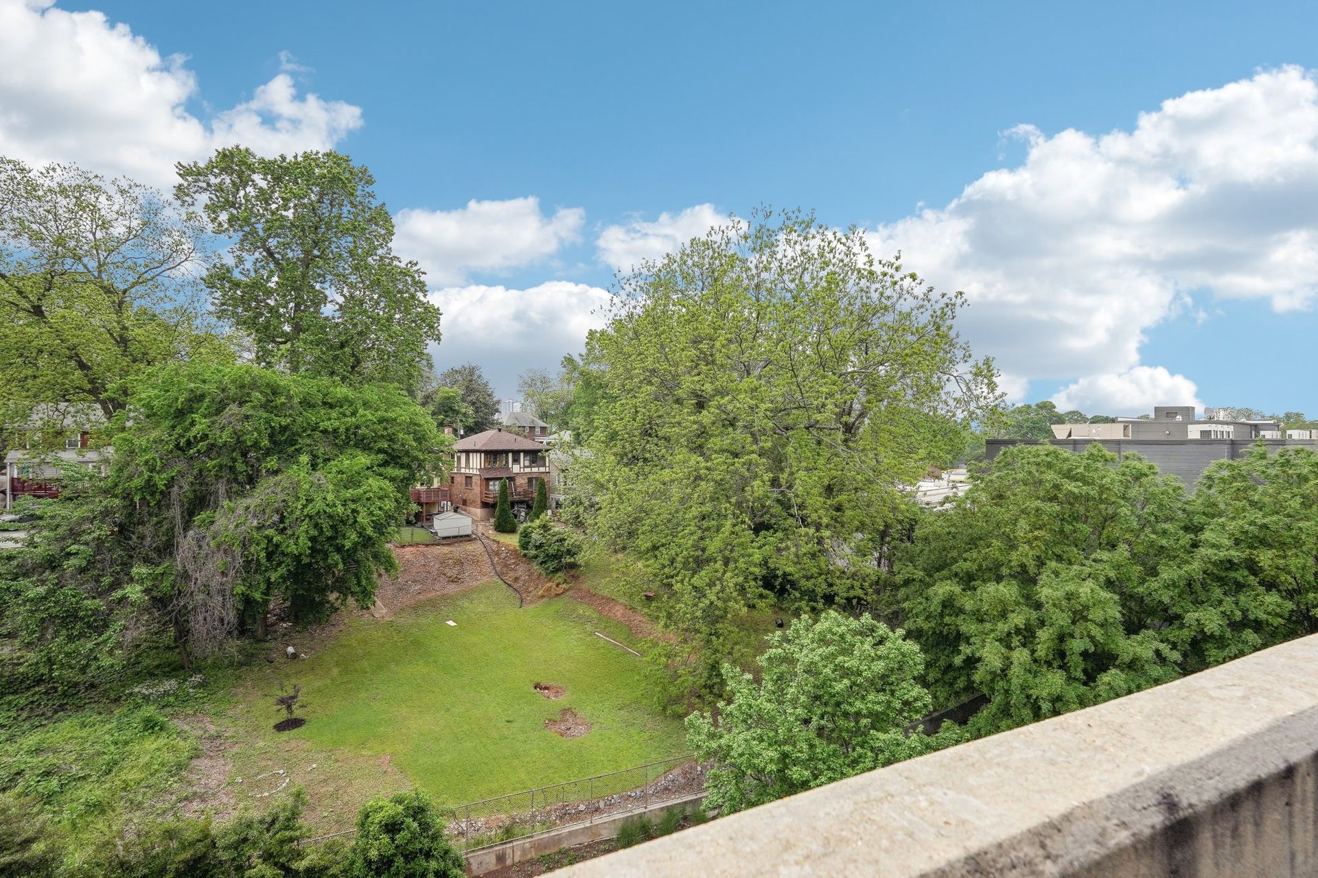 Green trees and grass under a blue sky, with a building in the background.