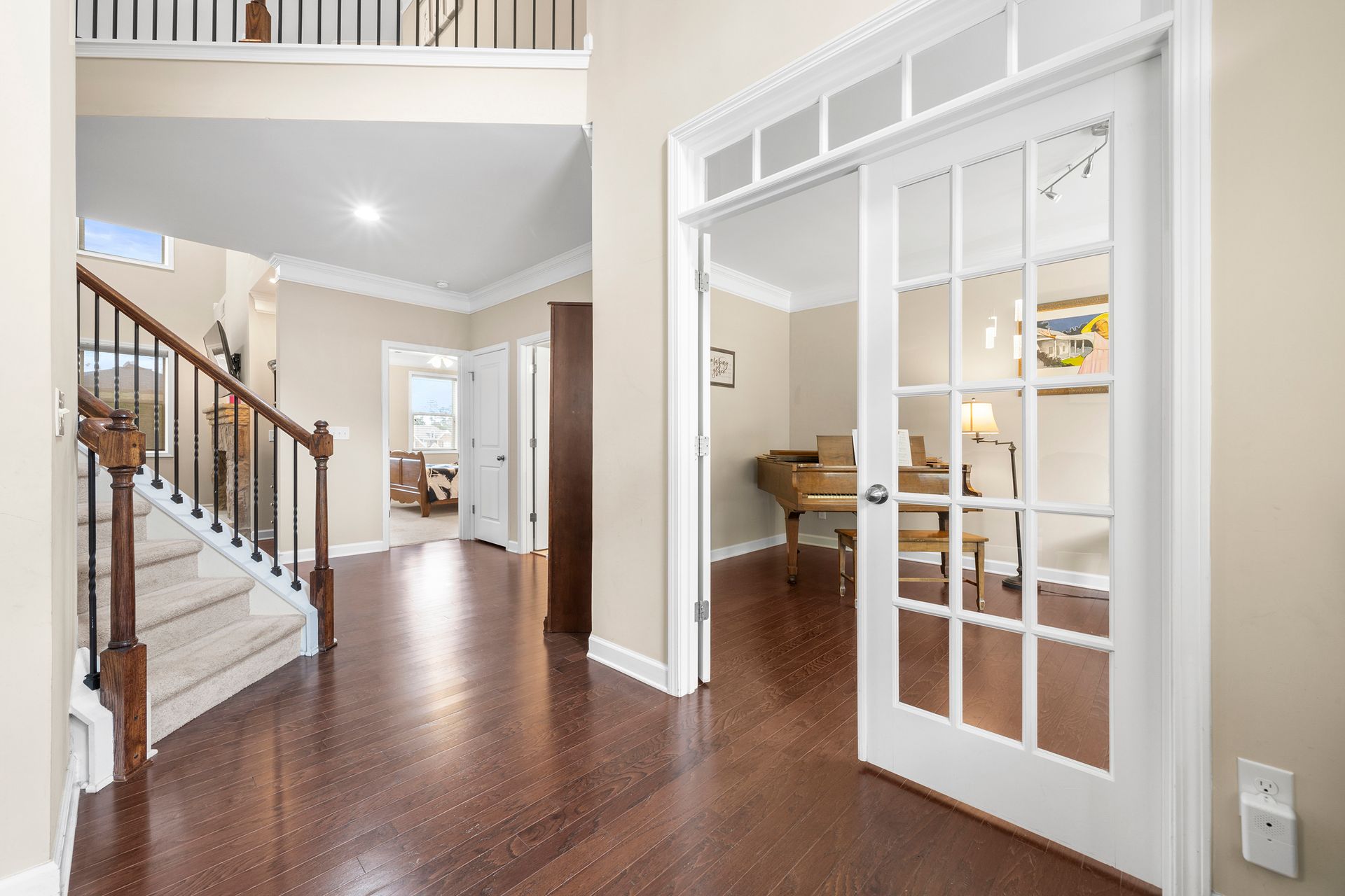 A hallway with hardwood floors and a staircase in a house.