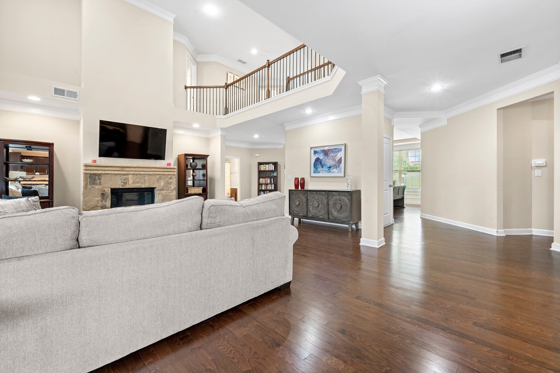 A living room with a couch , fireplace , television and hardwood floors.