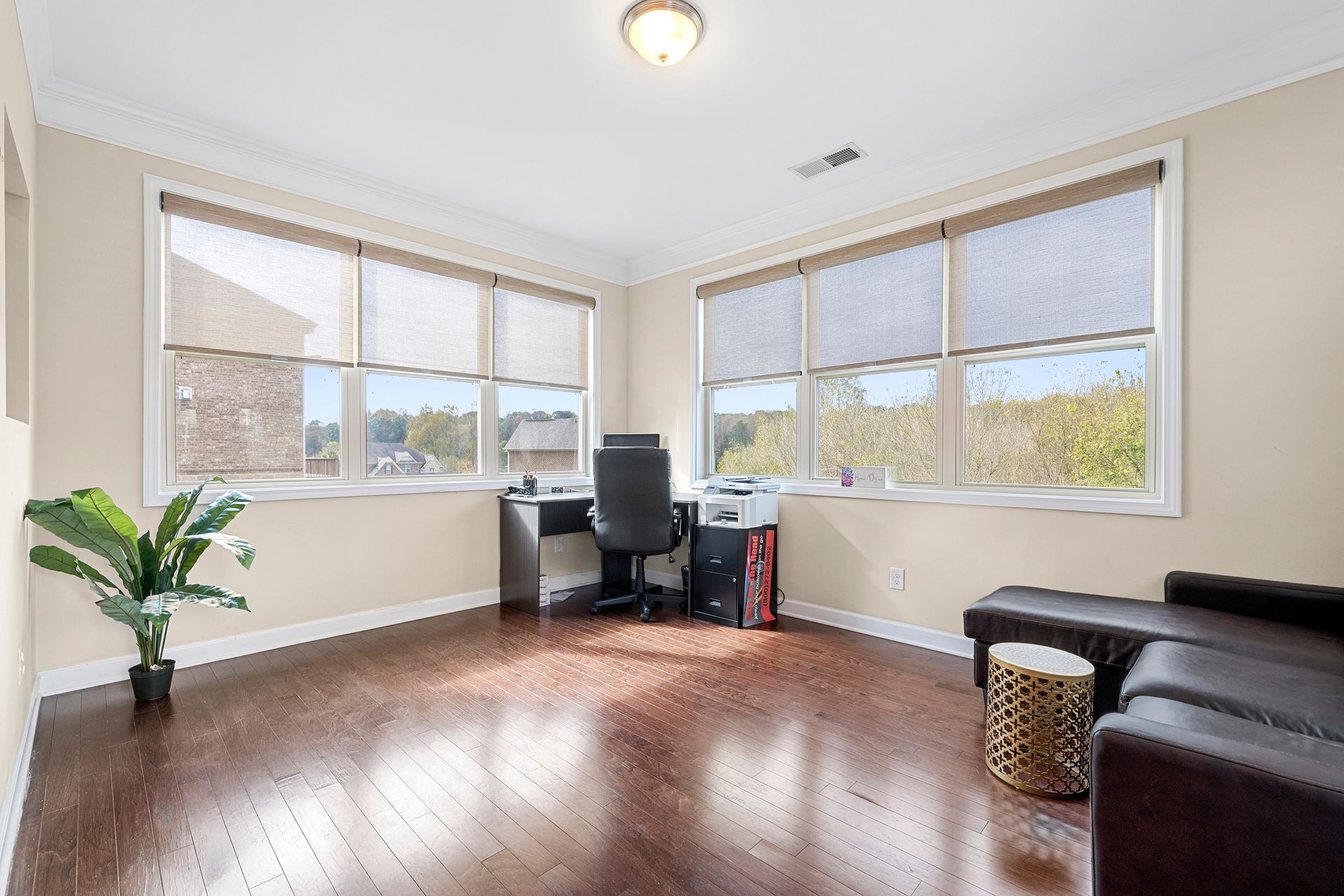 A living room with hardwood floors , a couch , a desk and a chair.