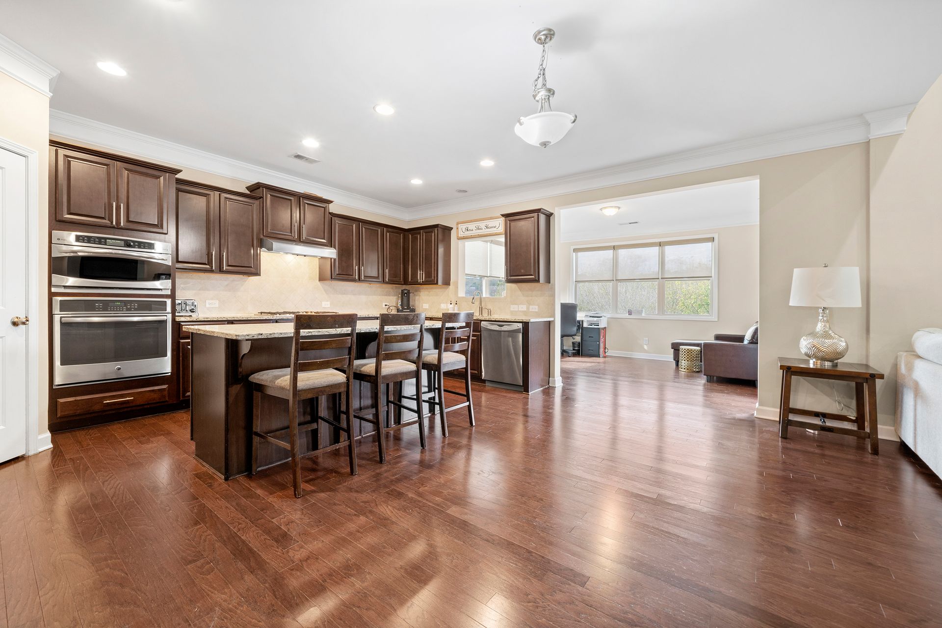 A kitchen and living room in a house with hardwood floors and stainless steel appliances.