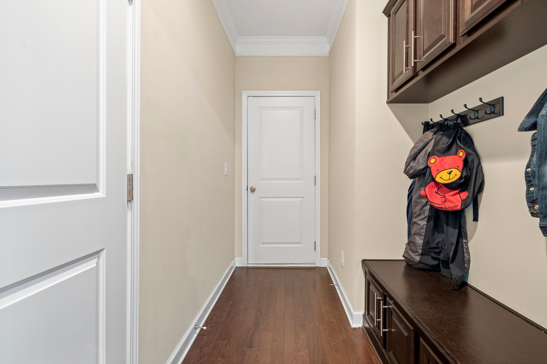 A hallway with a bench and a backpack hanging on the wall.
