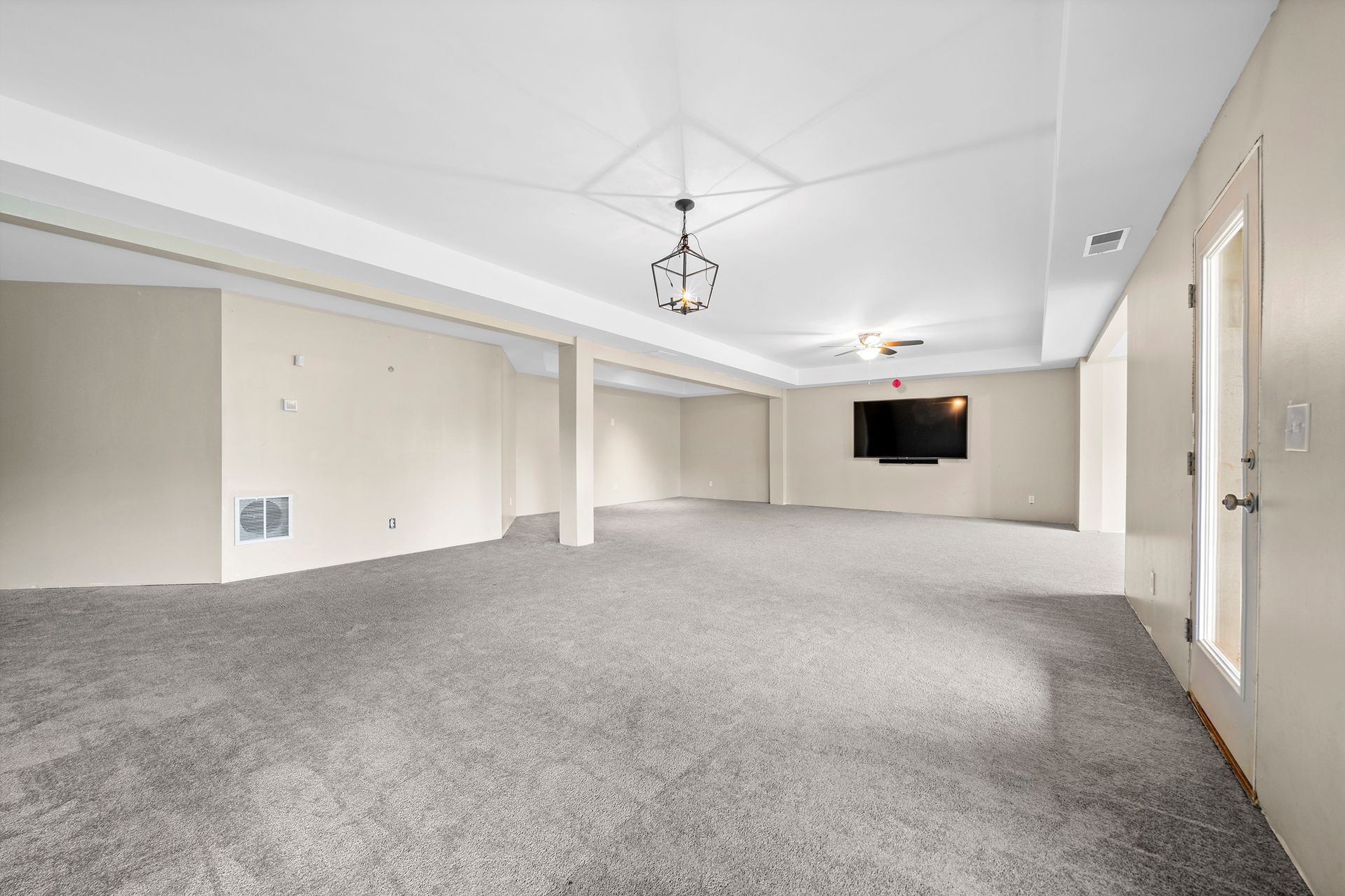 An empty basement with a flat screen tv on the wall.