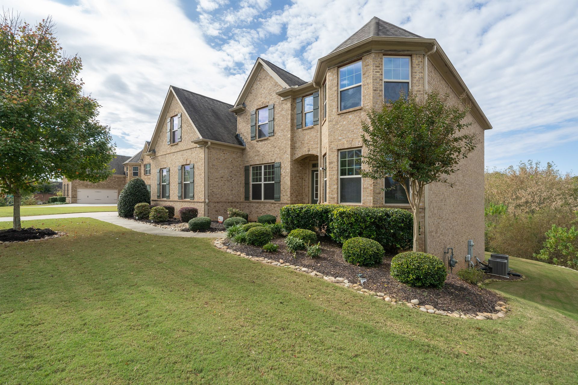 A large brick house with a lot of windows is sitting on top of a lush green hillside.