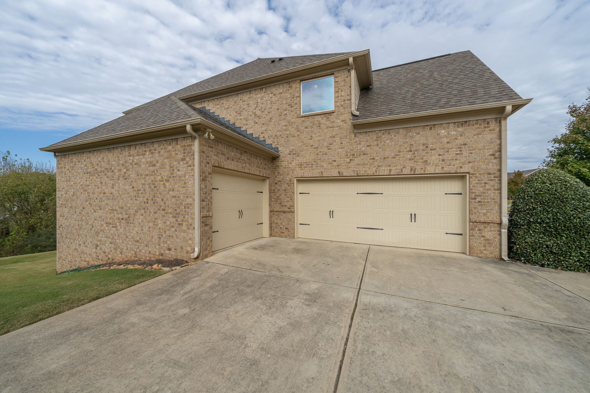 A large brick house with two garage doors and a driveway