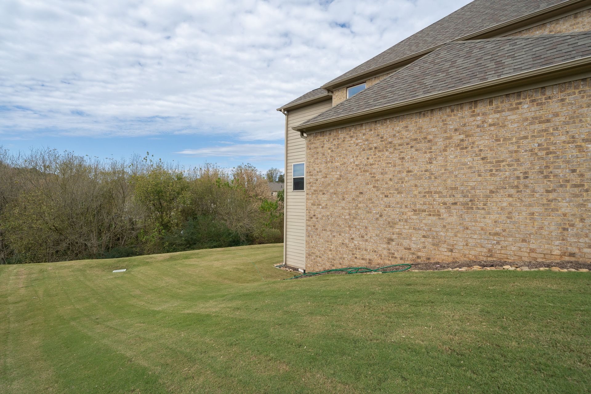 A large brick house with a large lawn in front of it.
