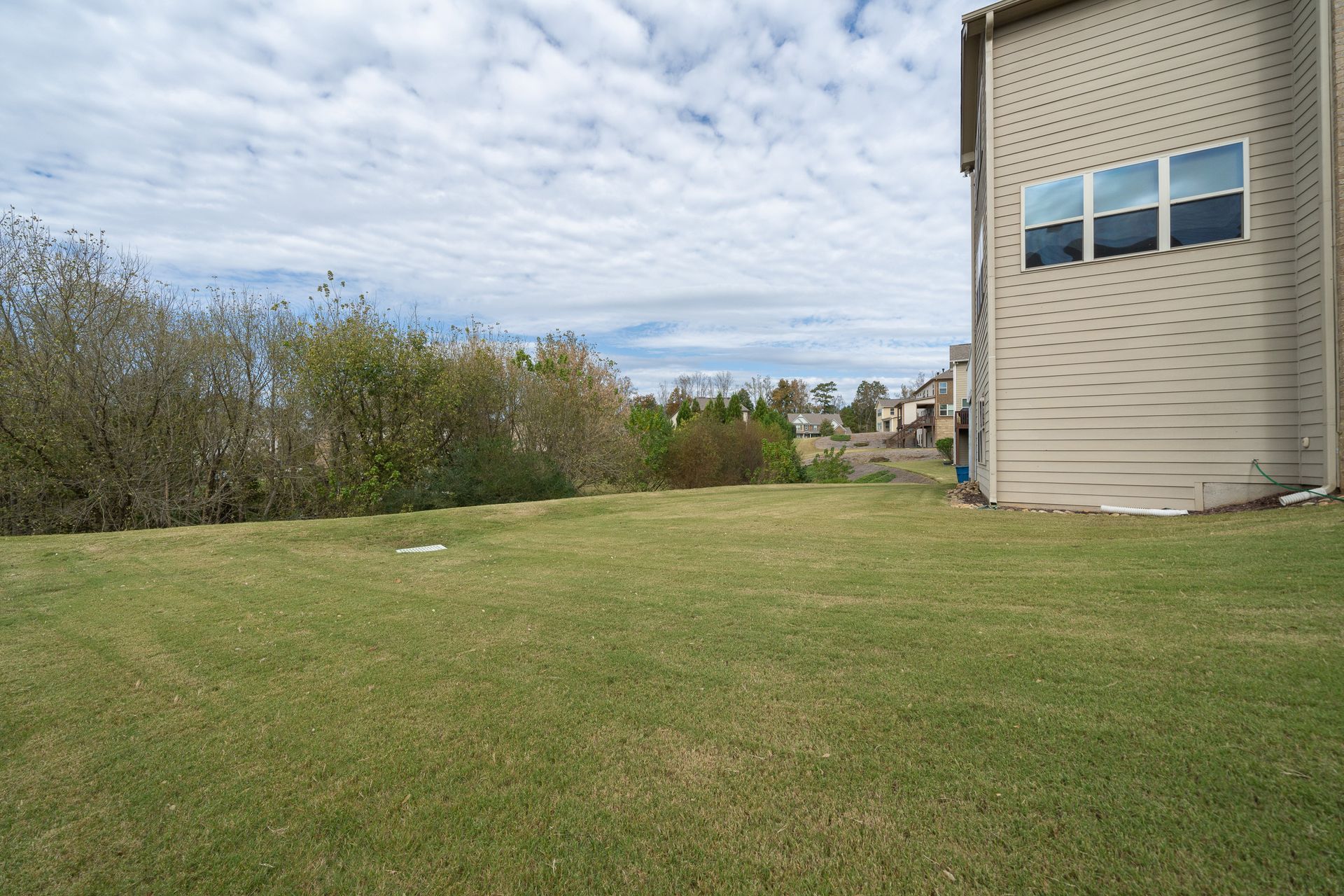 A large lawn in front of a house with a lot of windows.
