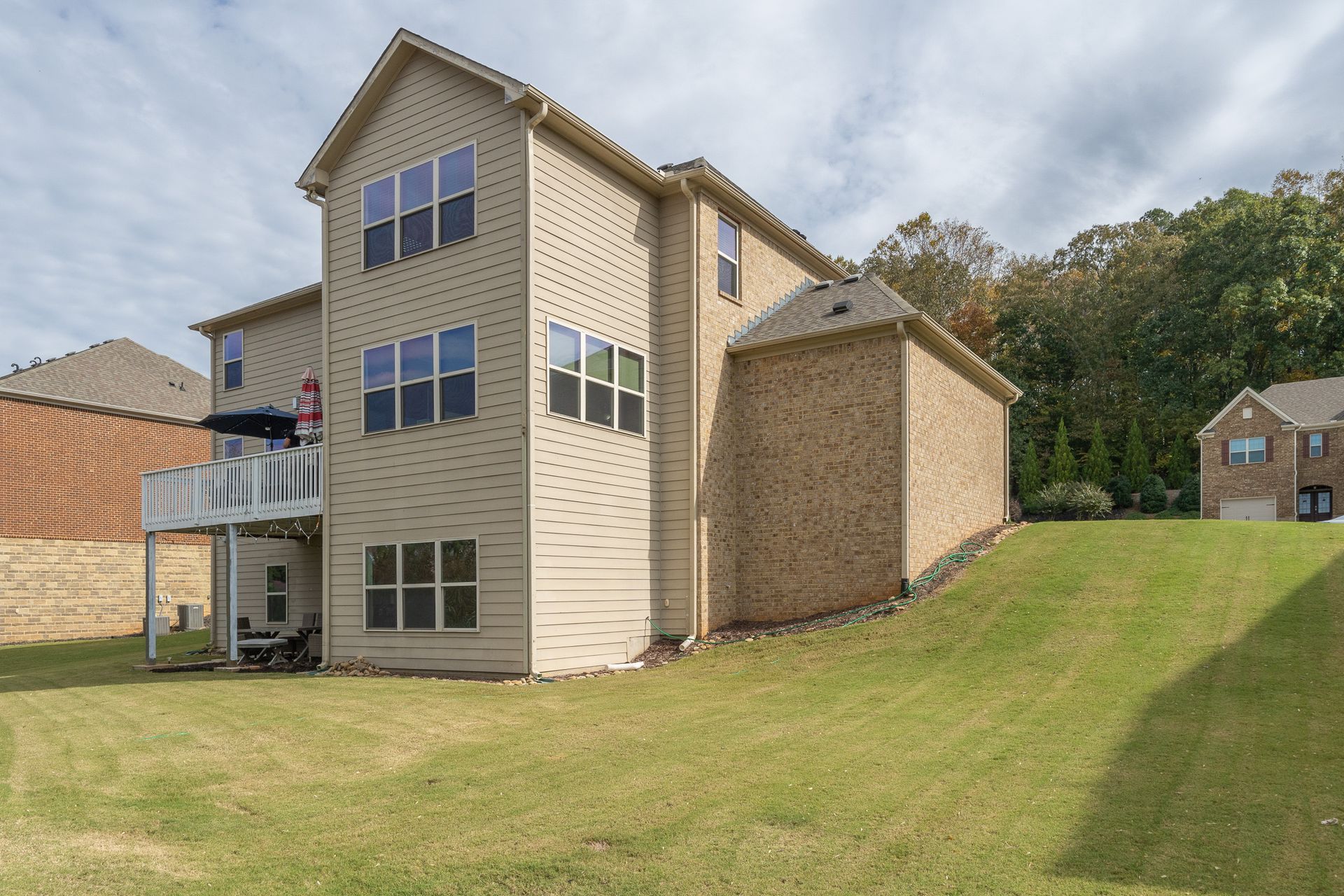 A large house with a lot of windows is sitting on top of a lush green hill.