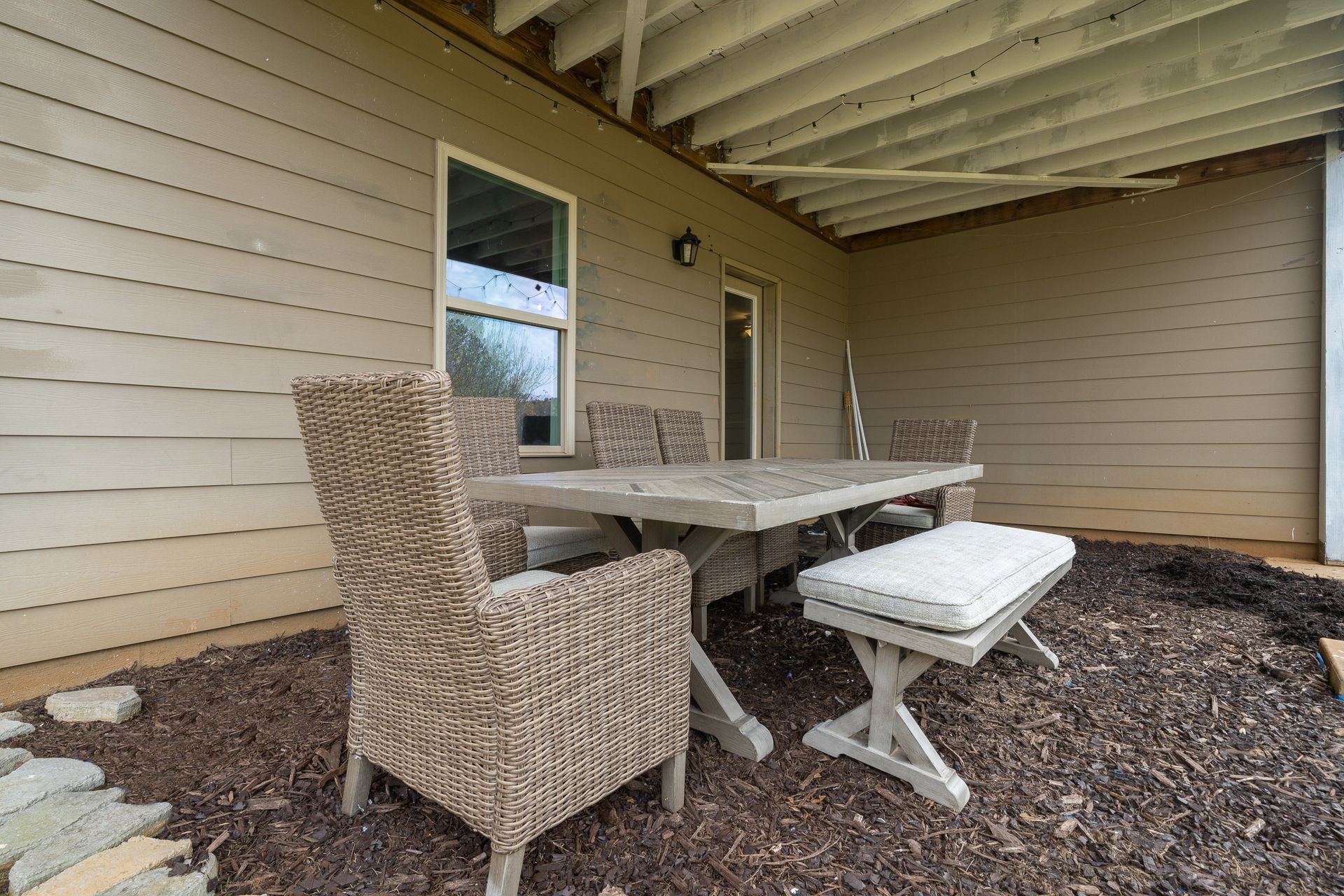 A patio with a table and chairs and a bench.