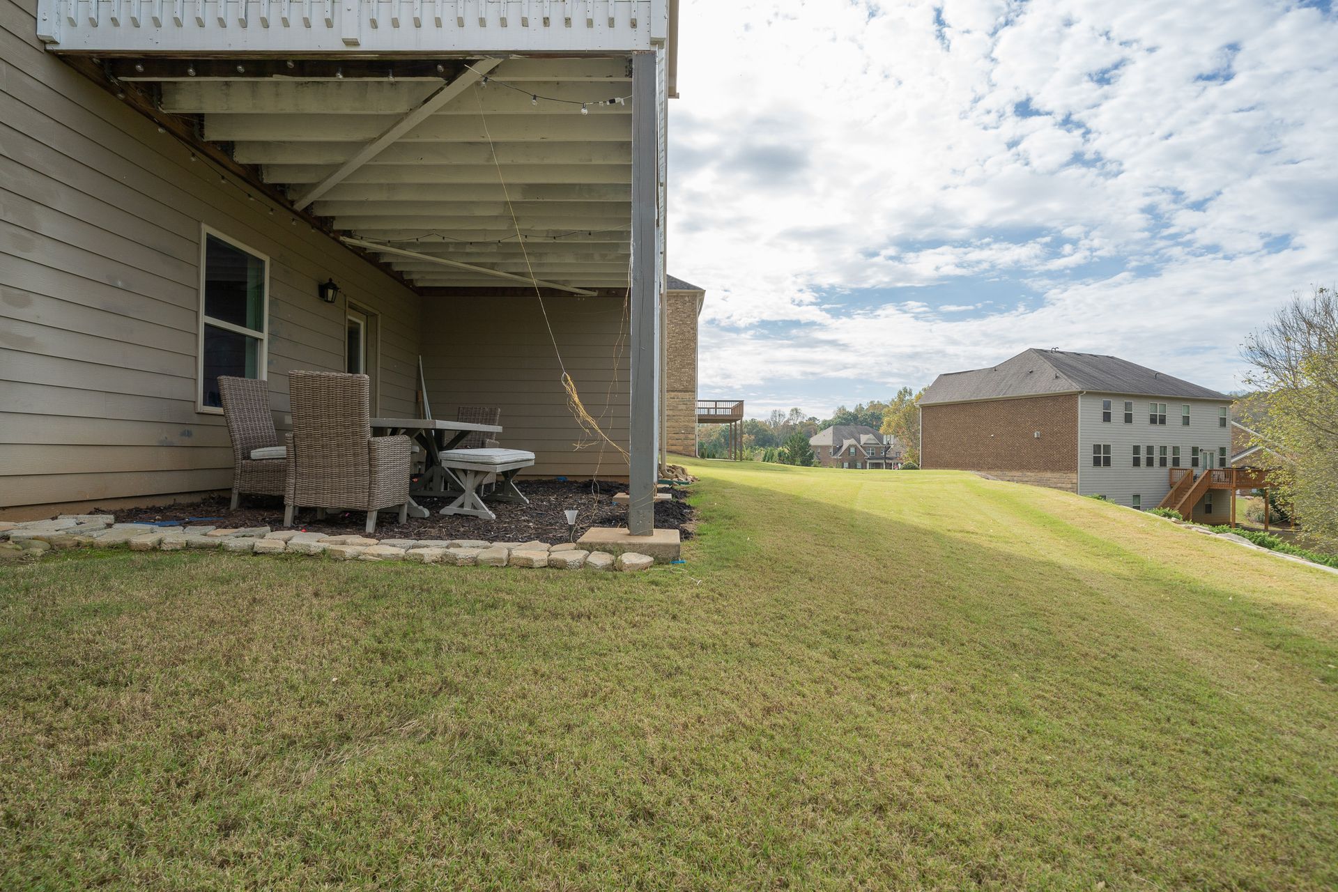 The backyard of a house with a covered patio and a table and chairs.